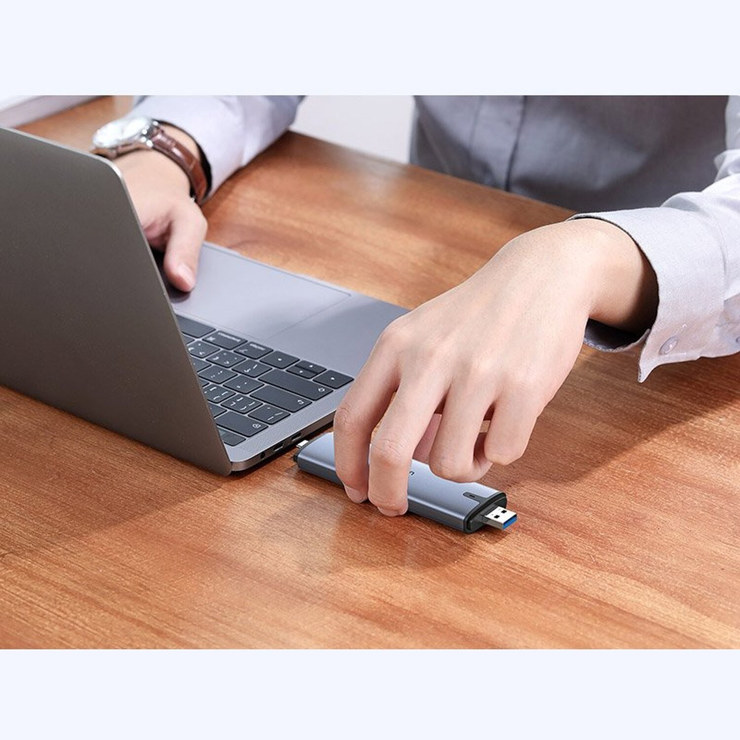 Person benutzt Laptop und steckt USB-Stick ein. Der USB-Stick ist silber und blau.