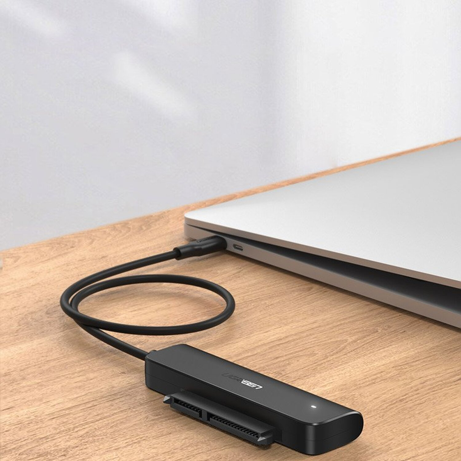 Schwarzer externer Festplattenadapter, über USB-C mit Laptop verbunden.