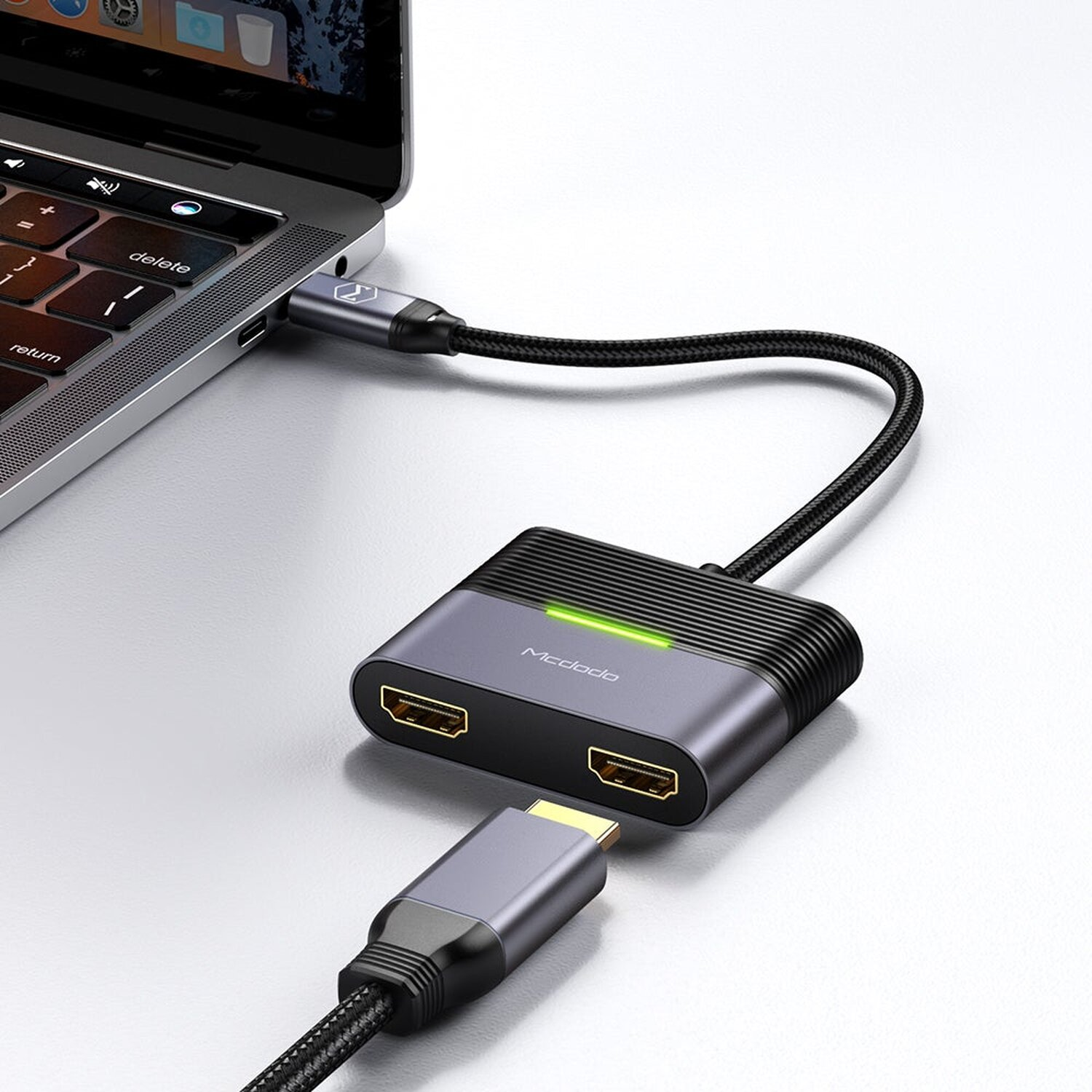 USB-C-Hub mit zwei HDMI-Anschlüssen, der an einen Laptop angeschlossen ist. Der Hintergrund ist weiß.