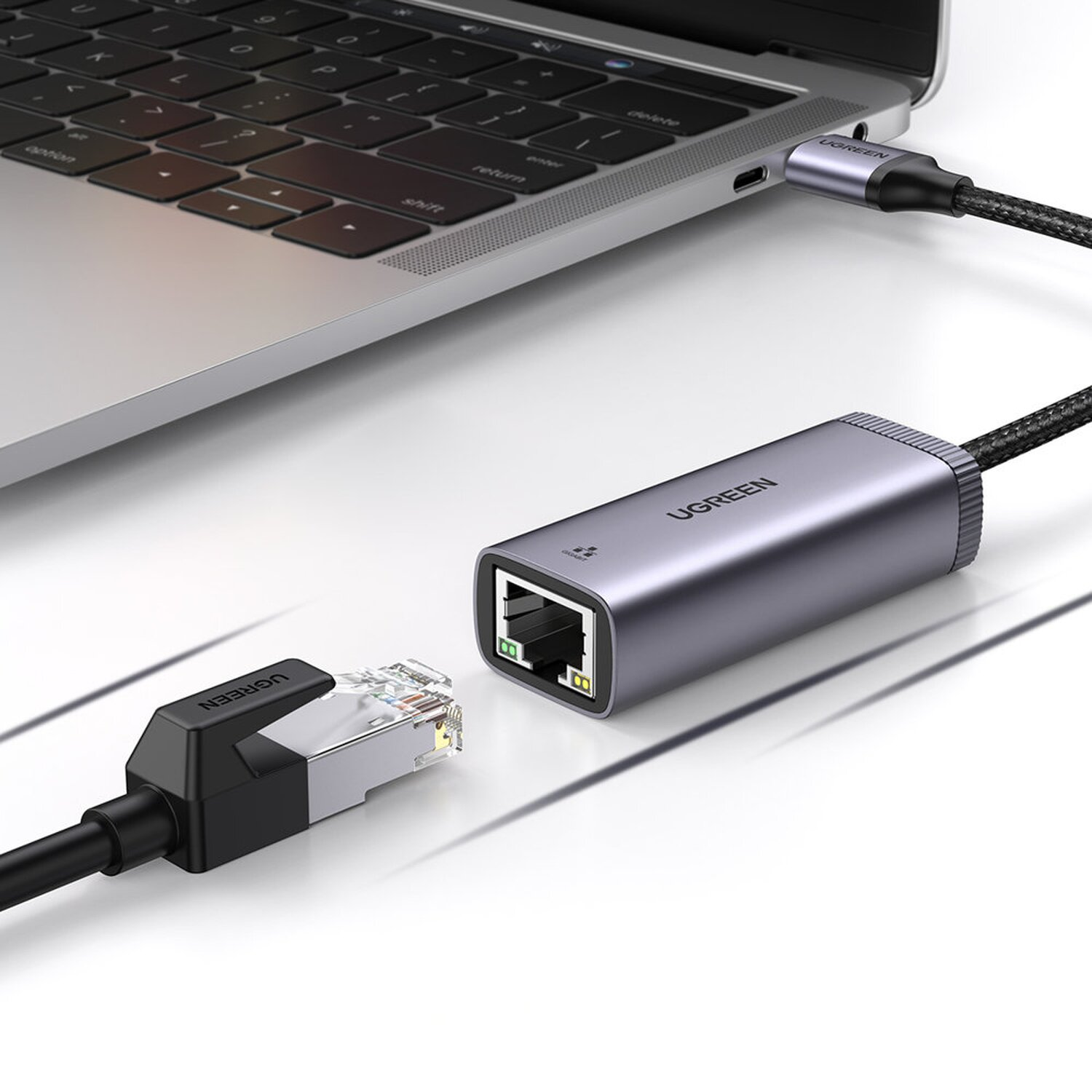 USB-C-zu-Ethernet-Adapter, der an einen Laptop angeschlossen ist. Ein schwarzes Kabel und ein silberner Adapter sind sichtbar.