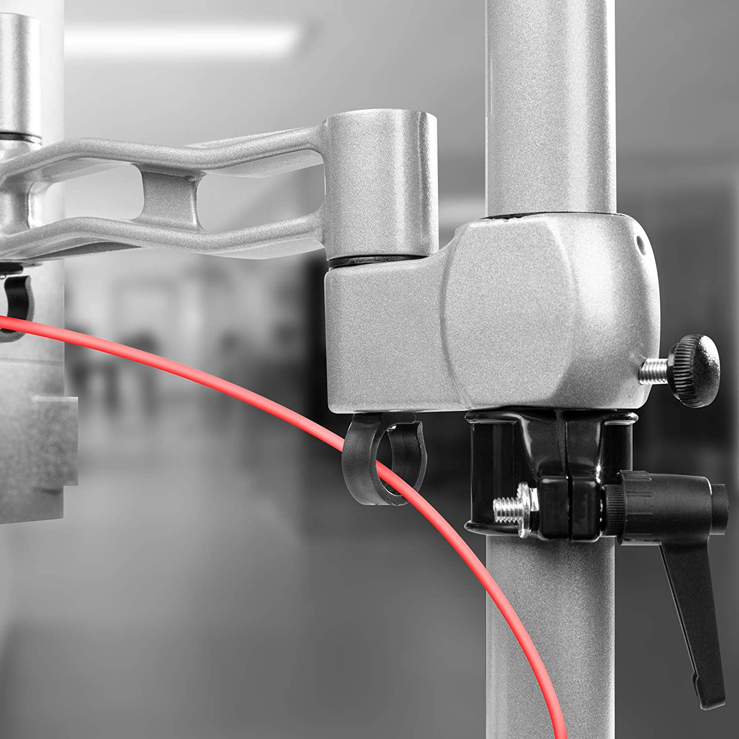 Primer plano de una estructura de soporte metálica con un cable rojo. La estructura tiene una abrazadera ajustable.