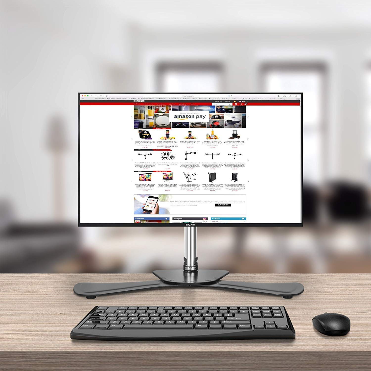 Un monitor de ordenador que muestra un sitio web con varios productos. Un teclado y un ratón están en el escritorio.