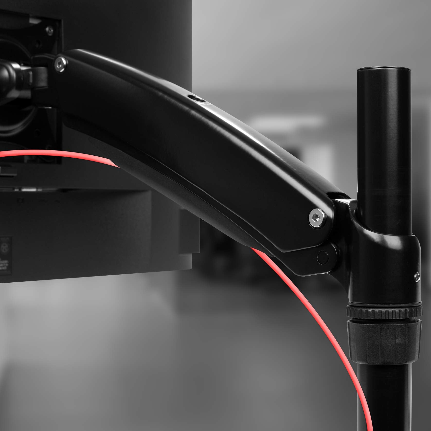 Schwarzer Monitorarm und rotes Kabel. Der Arm ist mit einem Monitor und einem schwarzen Pol verbunden.