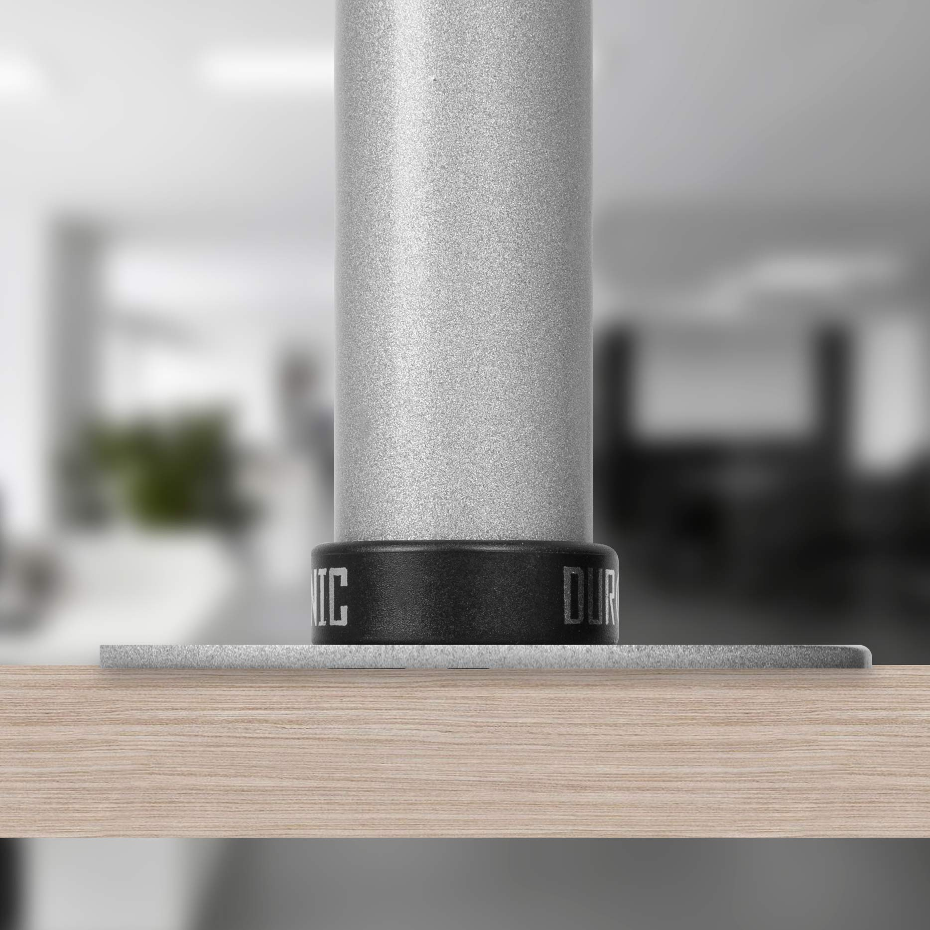 Una base de soporte de metal plateado sobre una superficie de madera con fondo borroso.
