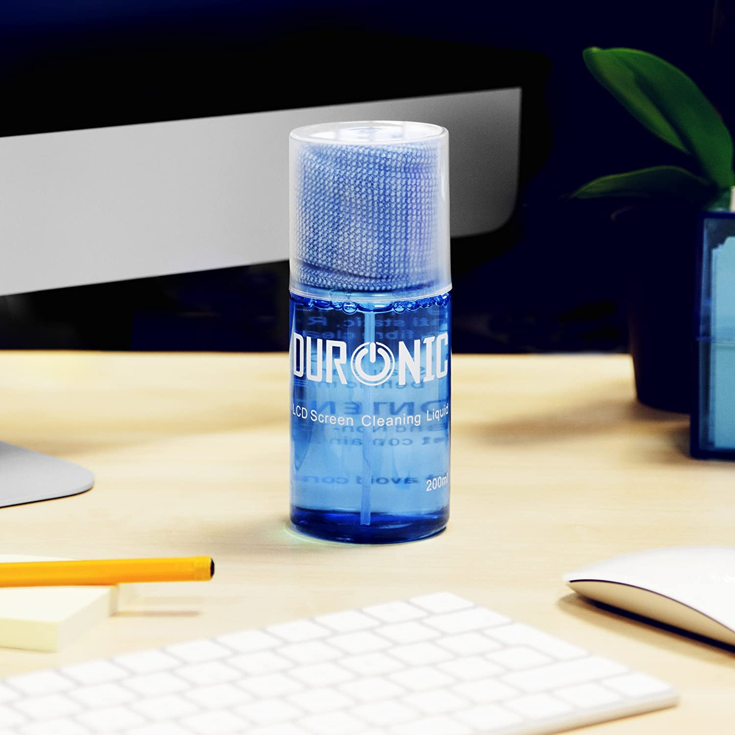 Eine blaue Reinigungsflasche, eine Tastatur, eine Maus und eine Pflanze auf einem Schreibtisch.