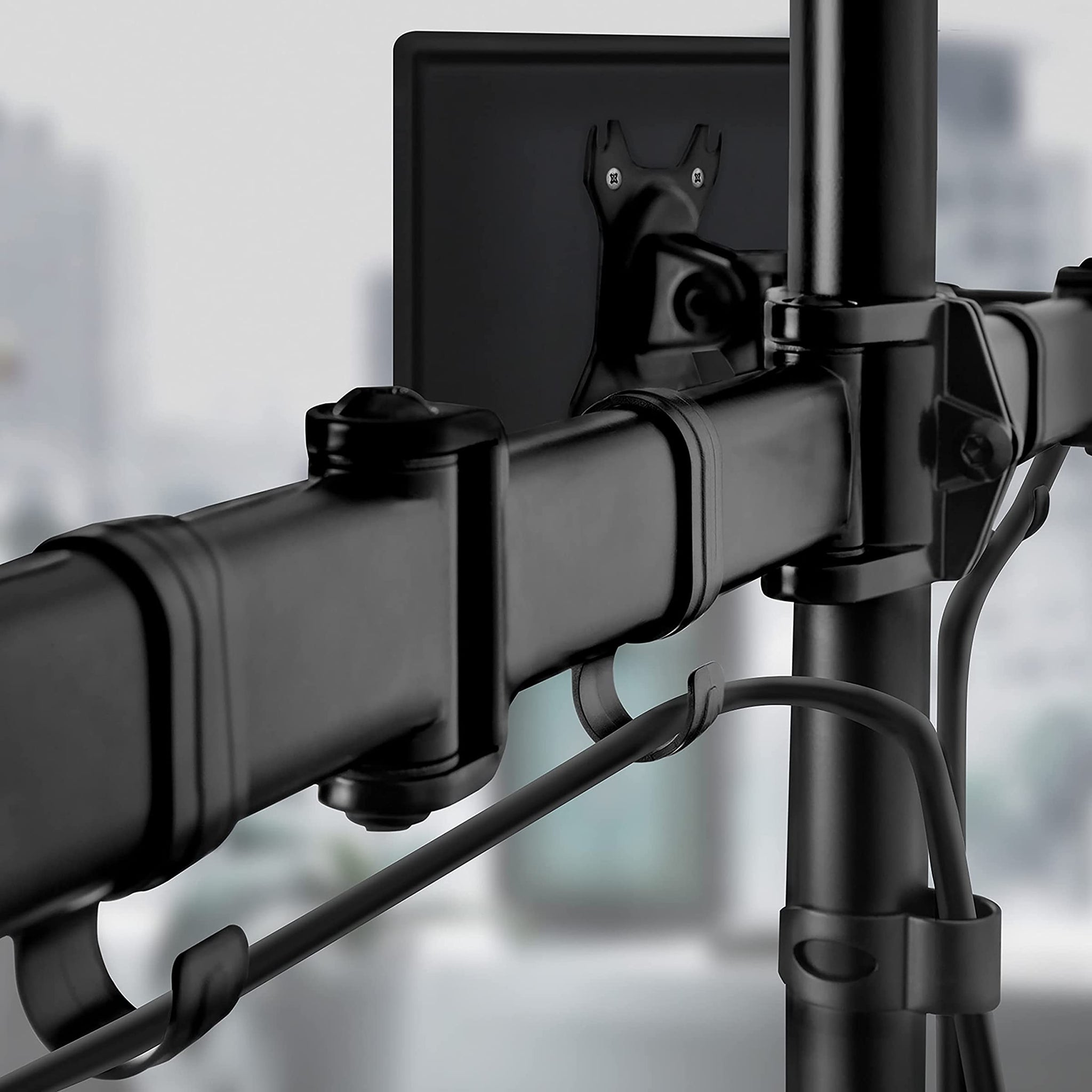Nahaufnahme eines schwarzen Monitorarms mit Kabeln und einer Monitorhalterung.