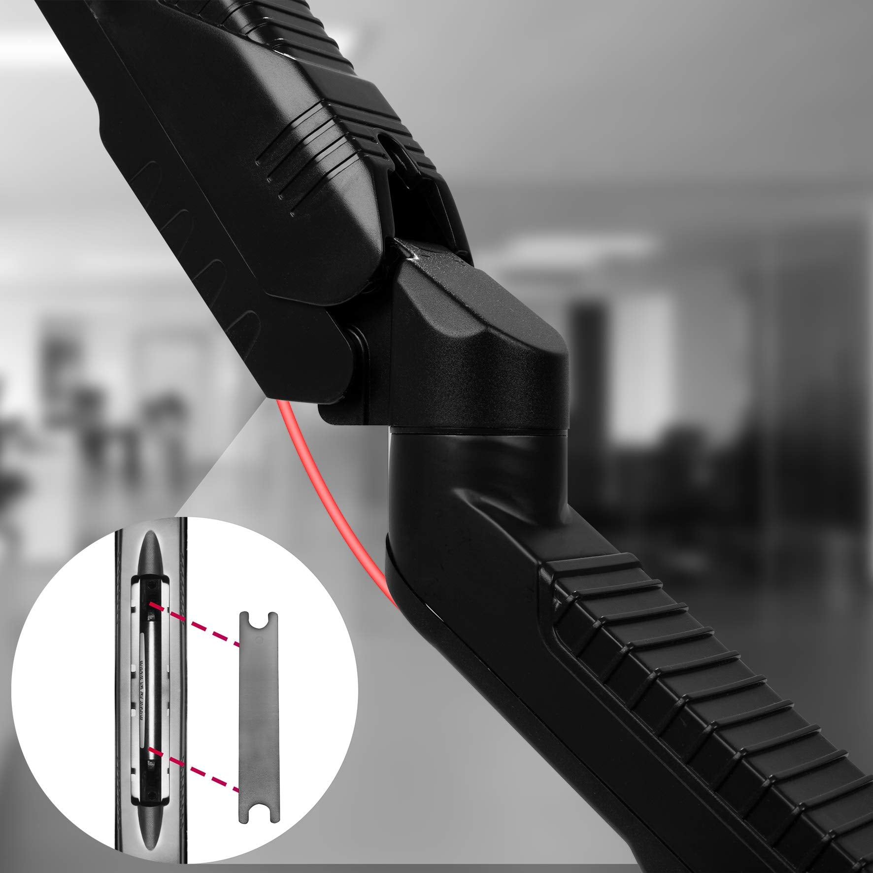 Nahaufnahme eines schwarzen Monitorarmgelenks mit roter Linie und kleinem Diagramm. Verschwommener Hintergrund.