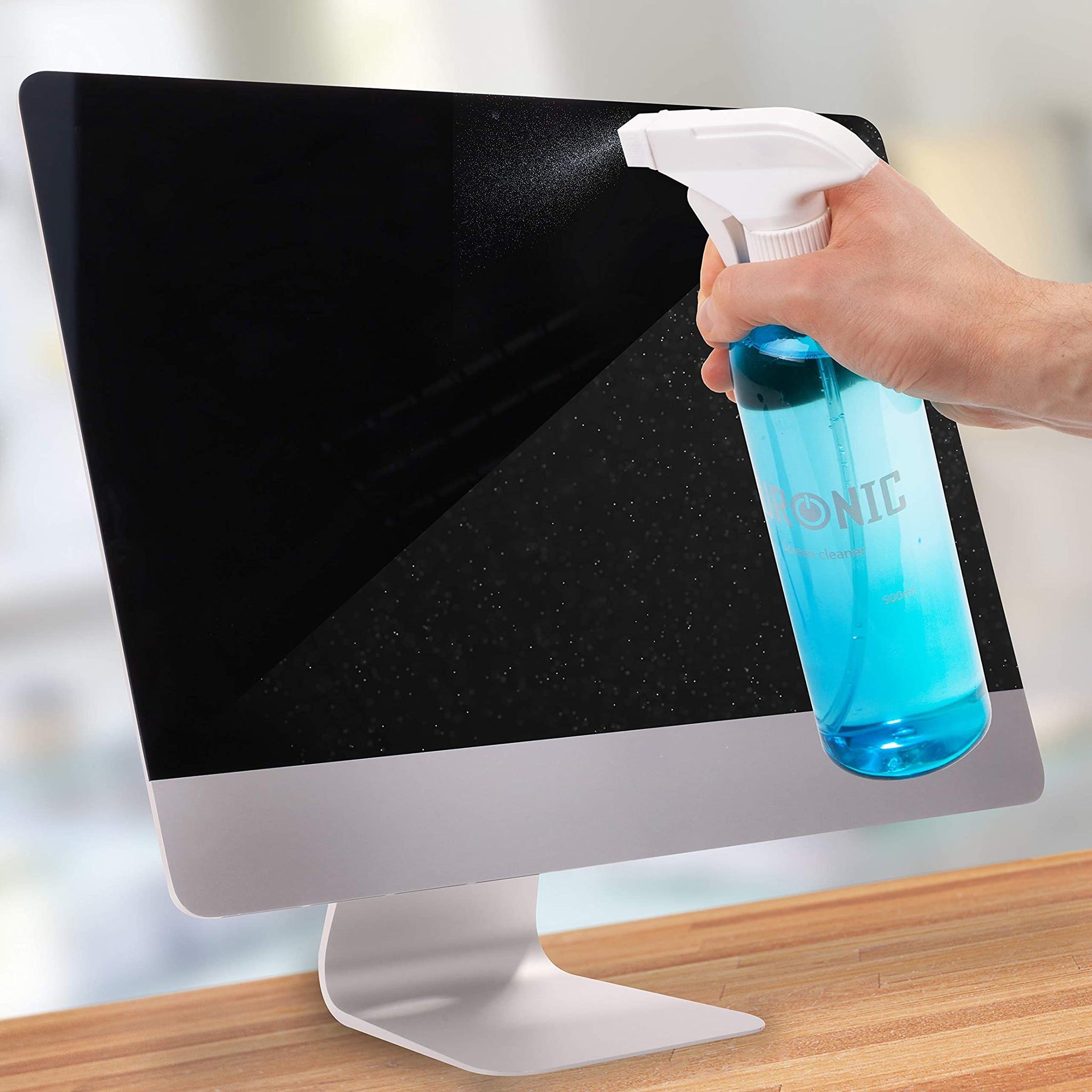 Eine Person besprüht einen Computerbildschirm mit einer blauen Reinigungslösung aus einer weißen Flasche.