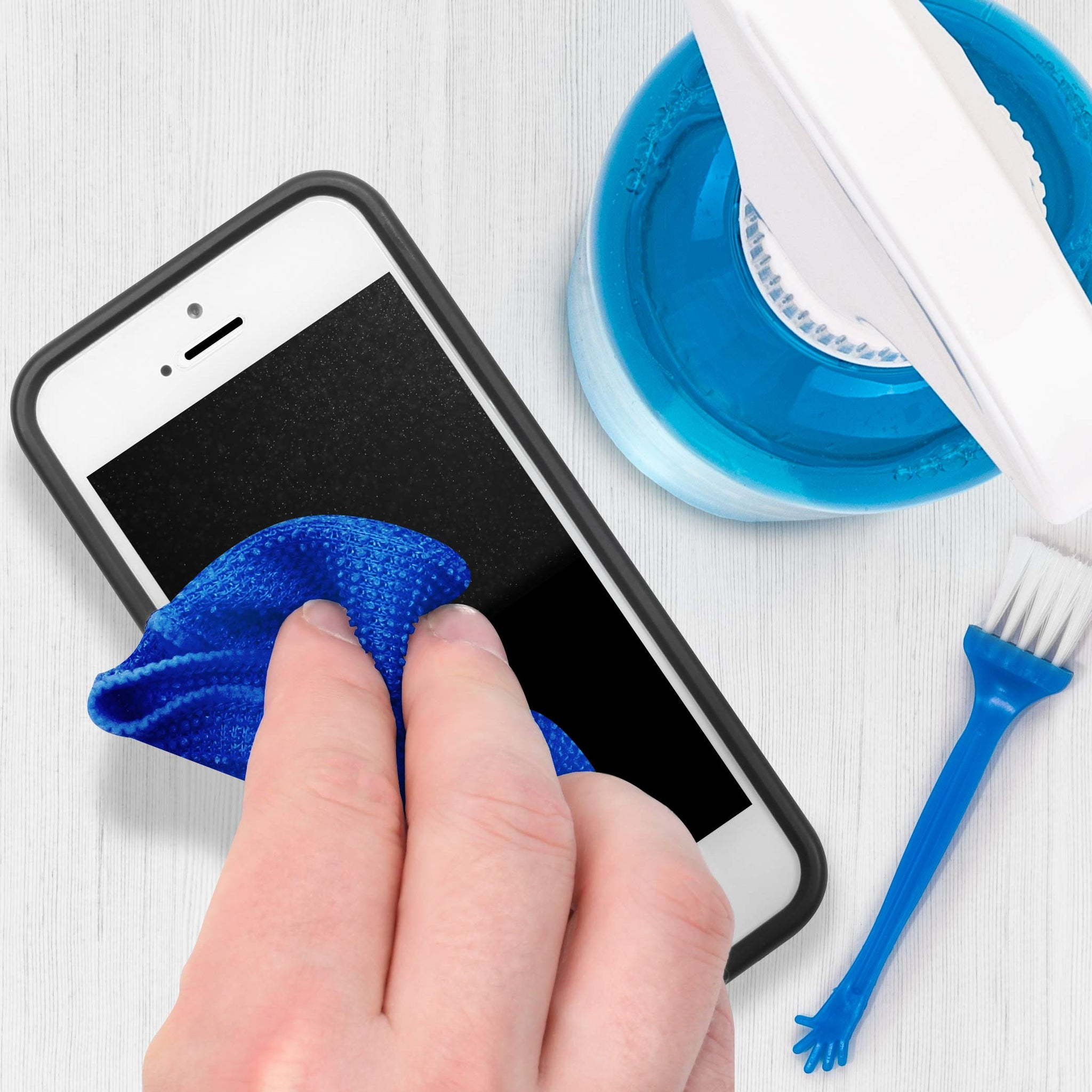 Eine Hand reinigt einen Smartphone-Bildschirm mit einem blauen Mikrofasertuch. Weitere Reinigungswerkzeuge sind vorhanden.