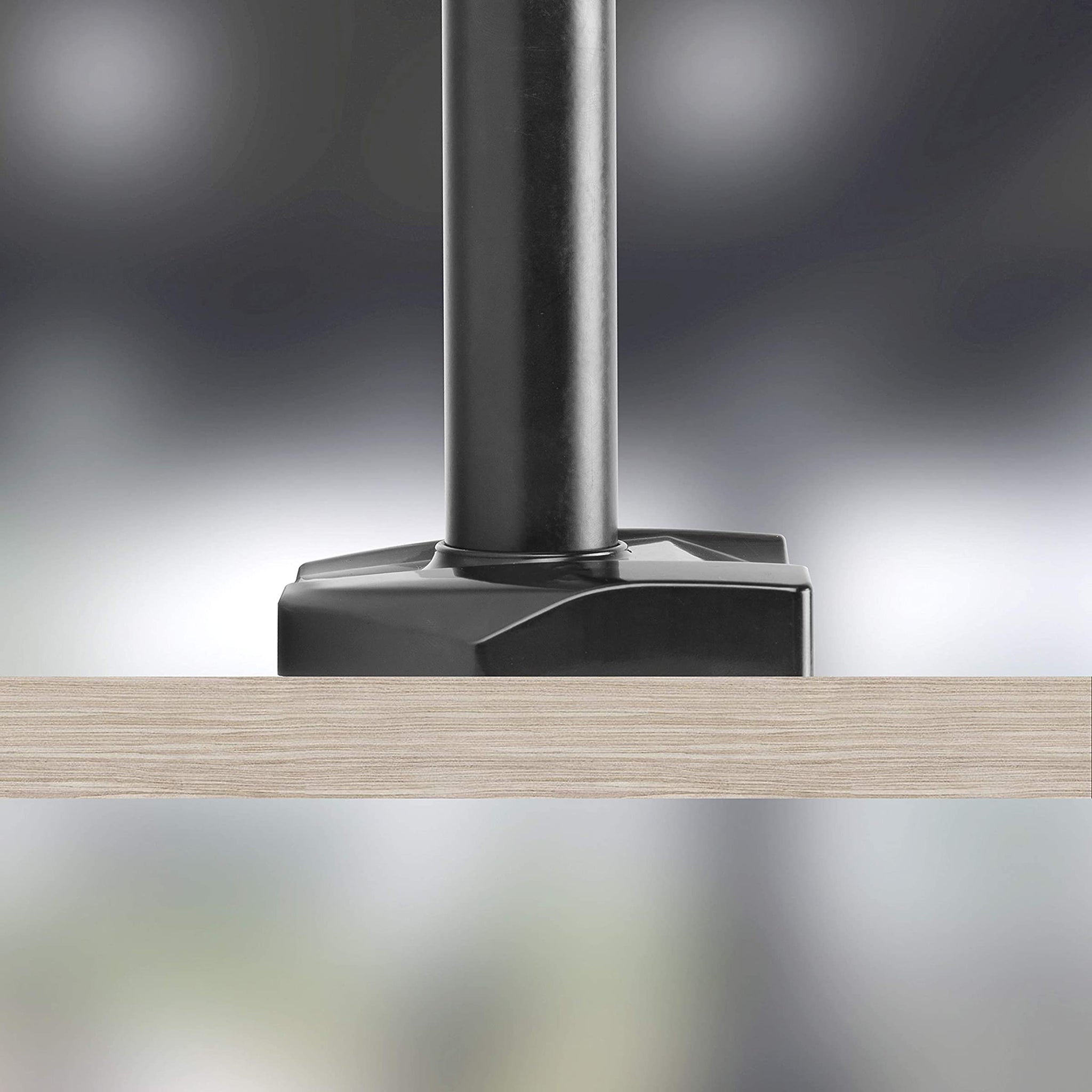 Primer plano de una base de brazo de monitor negro sujeta a una superficie de madera.