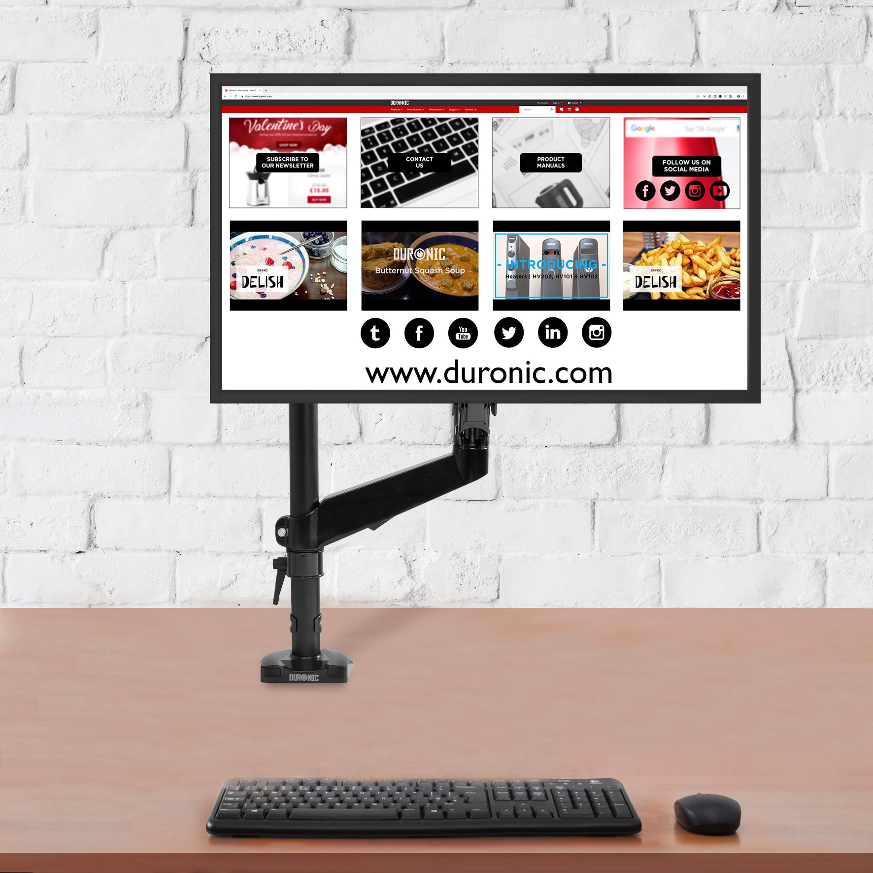 Monitor que muestra un sitio web en un escritorio. Teclado, ratón y un brazo de monitor en la escena.