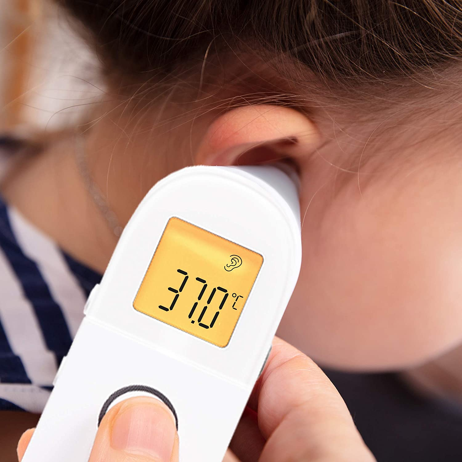 Das Ohr einer Person wird mit einem weißen Digitalthermometer untersucht, das 37,0 Grad Celsius anzeigt.