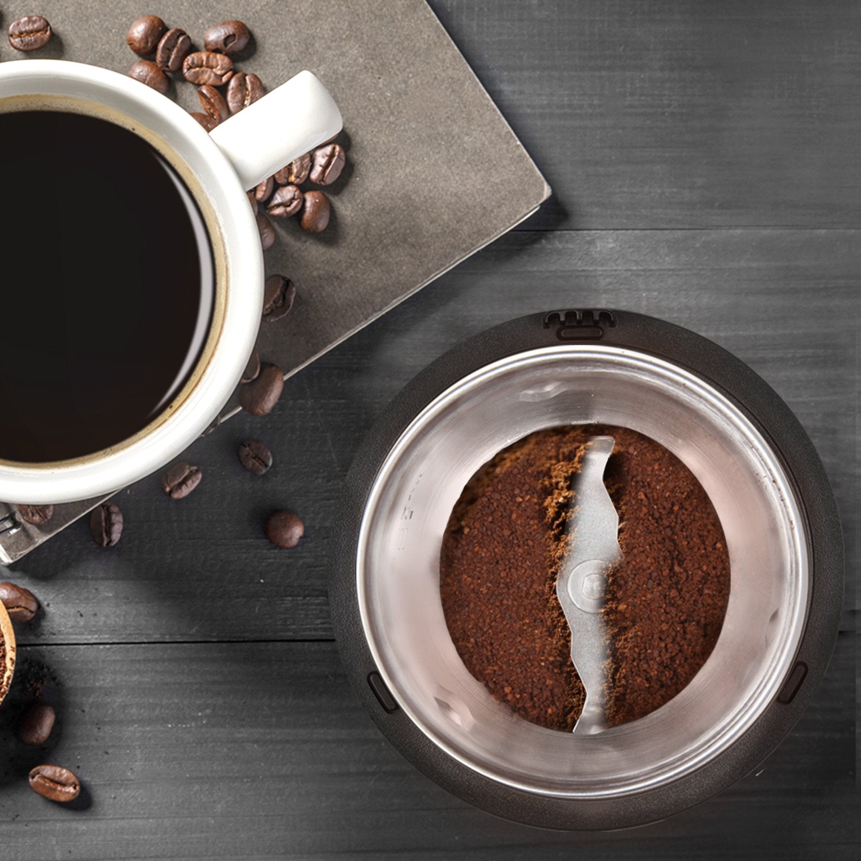 Draufsicht auf Kaffeetasse, Kaffeebohnen, Kaffeemühle mit Kaffeepulver auf grauer Holzoberfläche.