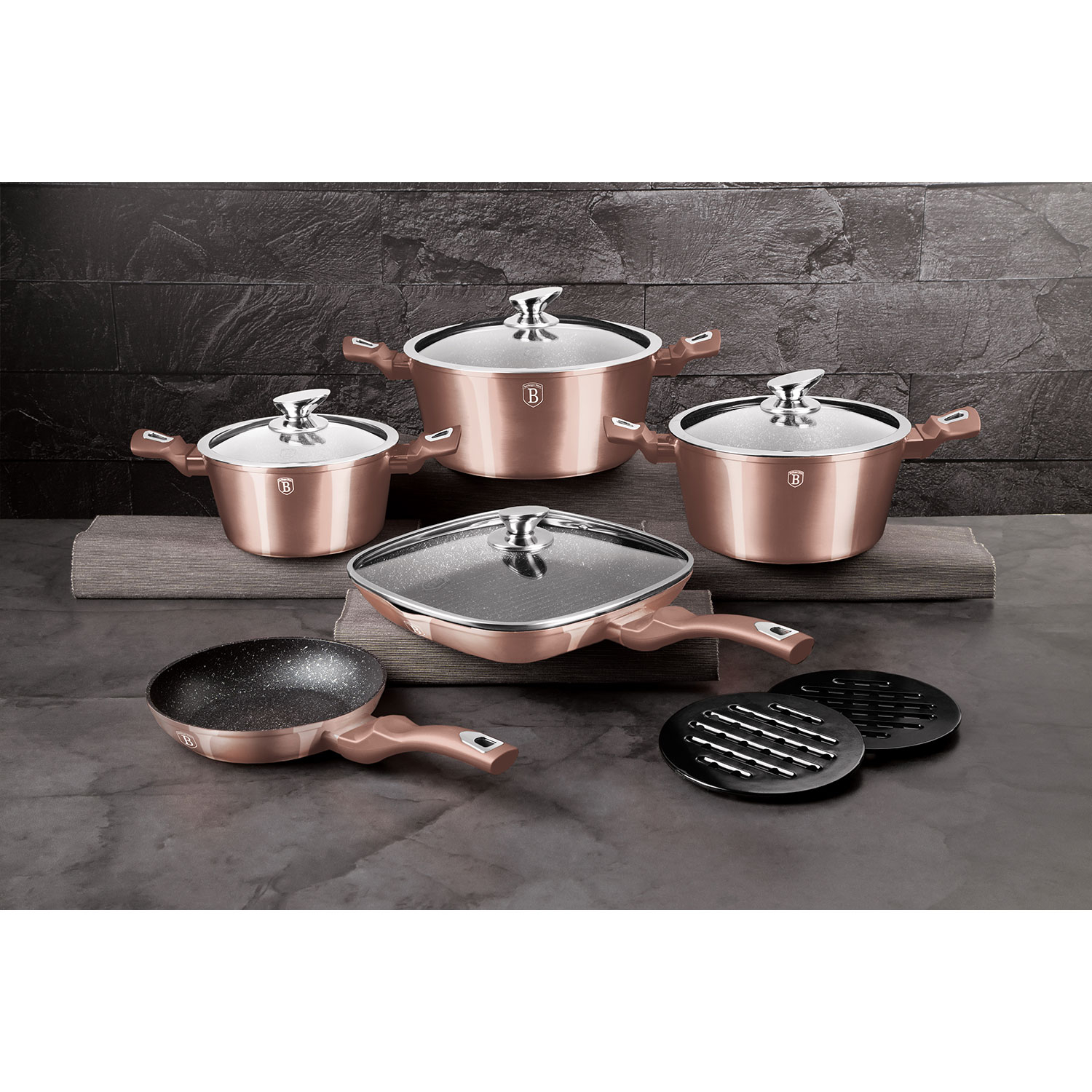 Juego de utensilios de cocina de cobre con ollas, sartenes y utensilios sobre una superficie oscura.