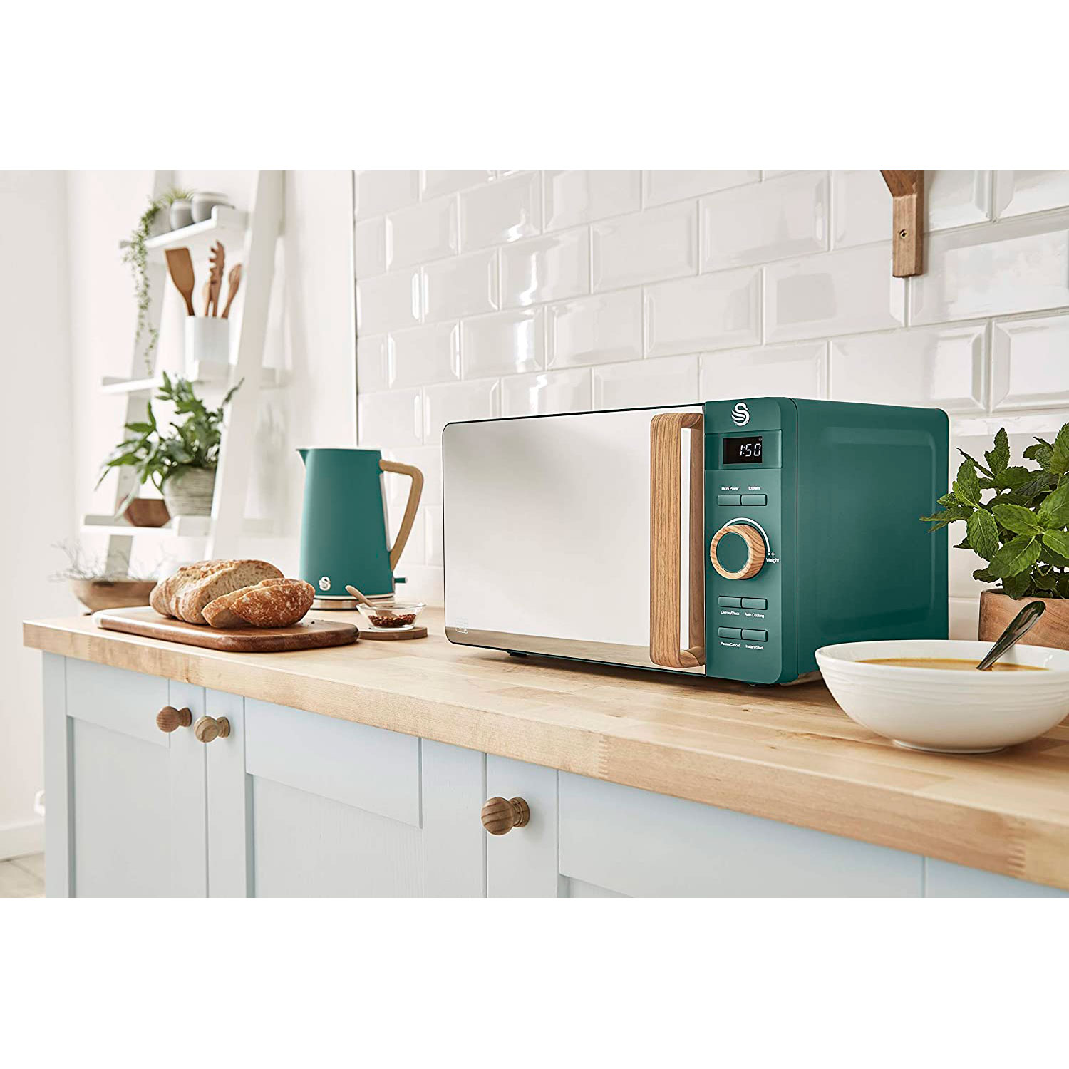 Un horno microondas verde azulado con mango y molduras de madera está sobre una encimera de cocina con comida.