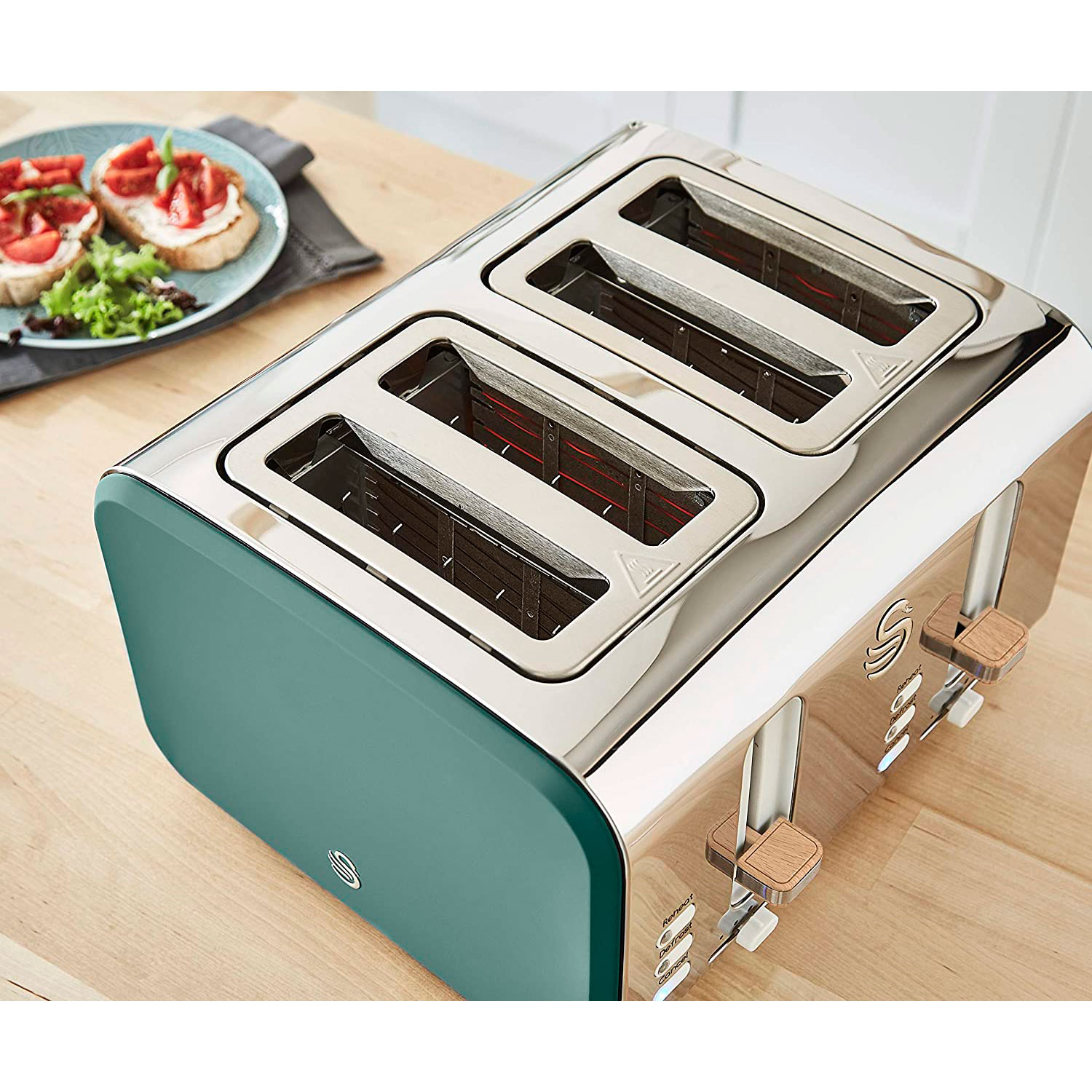 Ein türkis-silberner Toaster mit drei Schlitzen. Toastscheiben mit Belag liegen auf einem Teller.