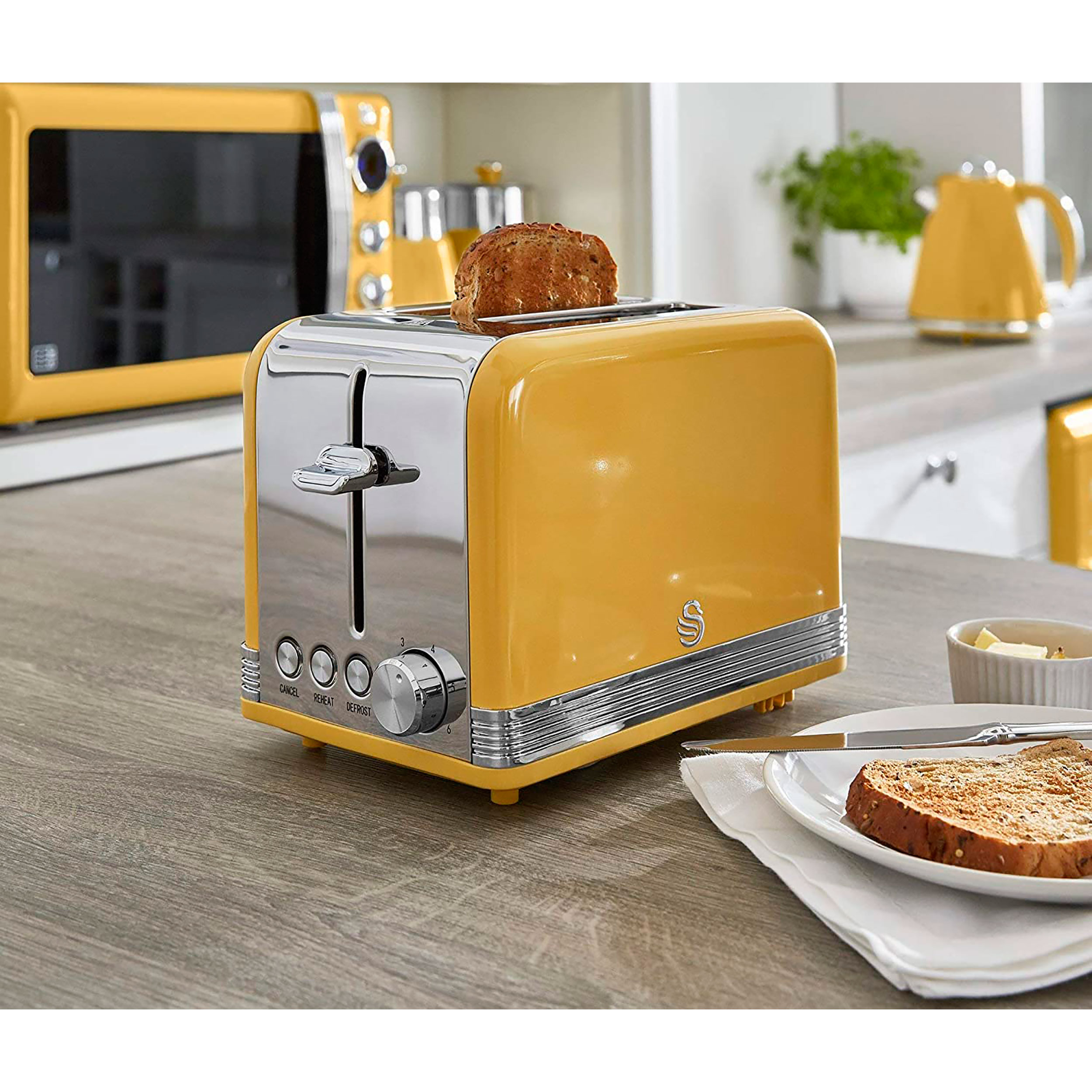 Ein gelber Toaster mit Toast, einer Mikrowelle und einem Wasserkocher.