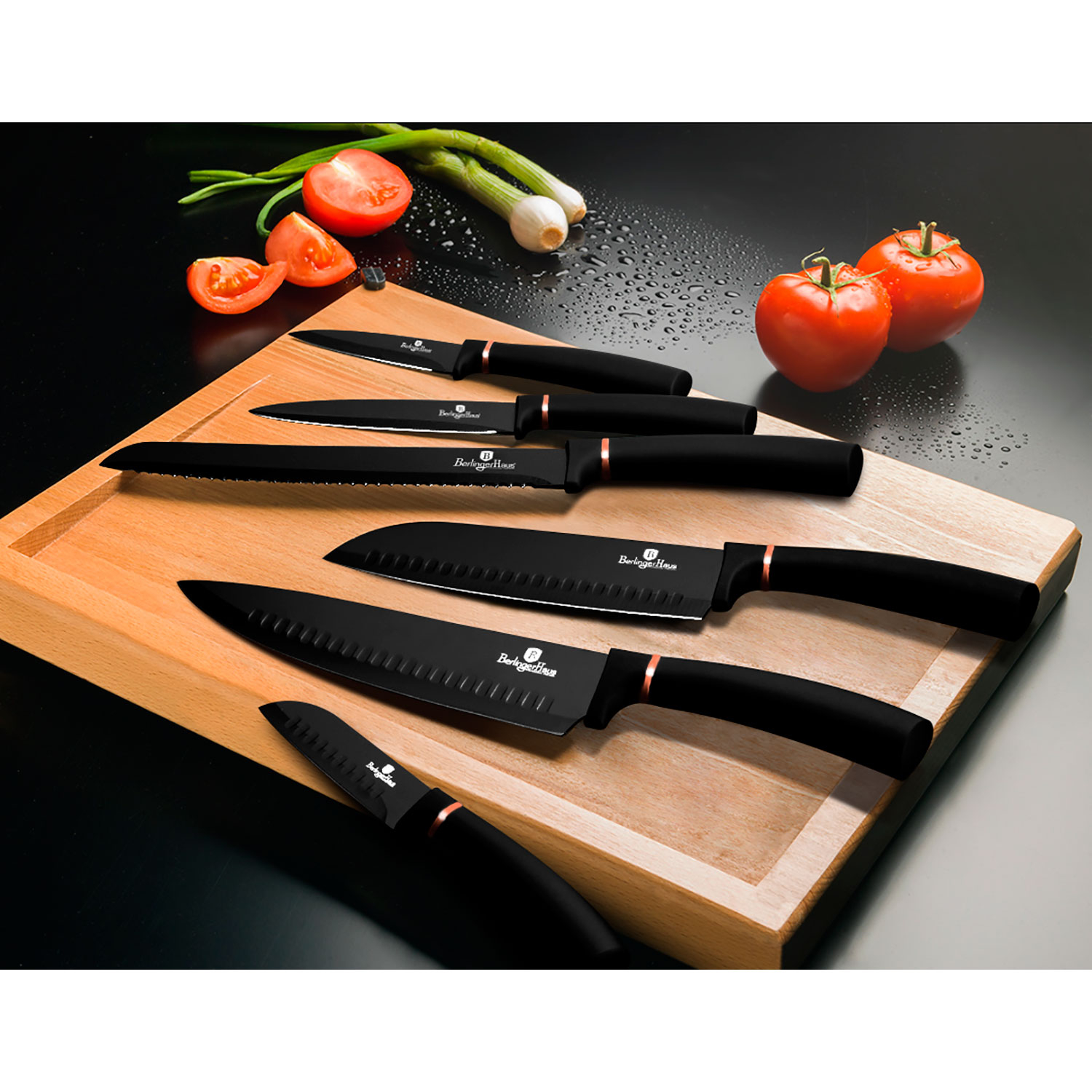 Juego de cuchillos negros sobre una tabla de madera, con tomates y cebolletas.