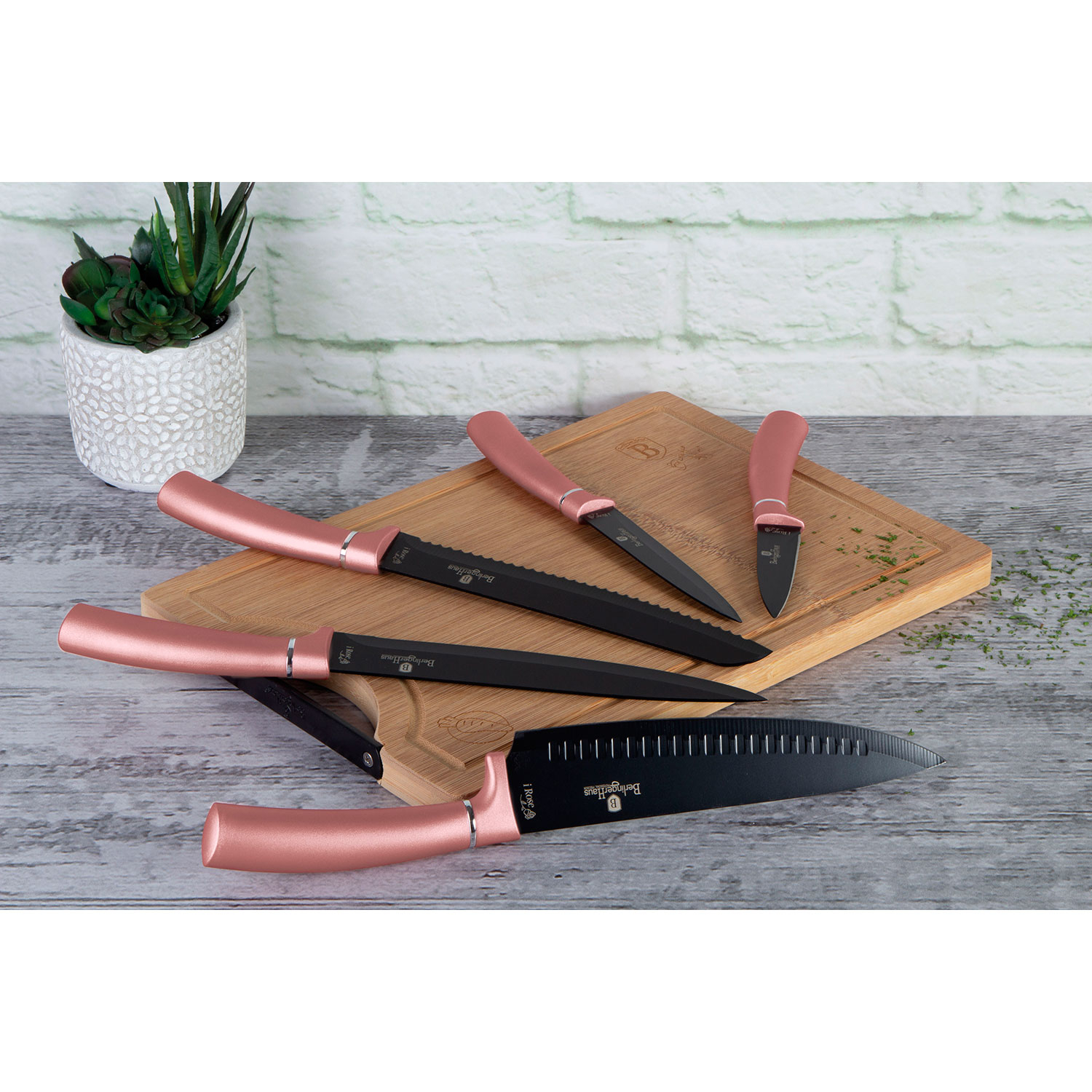 Juego de cuchillos de cocina con mangos oro rosa sobre tabla de cortar de madera.