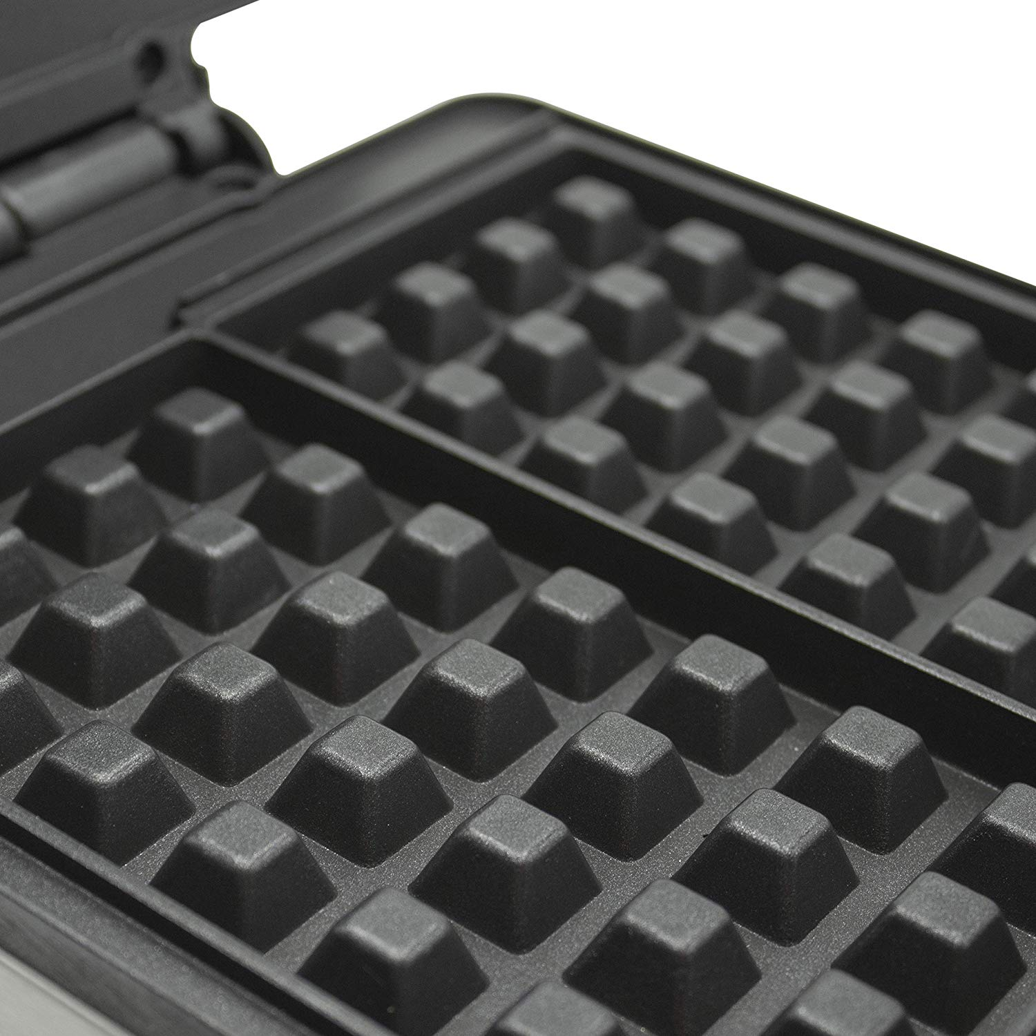 Wnętrze gofrownicy pokazujące powierzchnię do pieczenia. Czarne, kwadratowe foremki do gofrów.