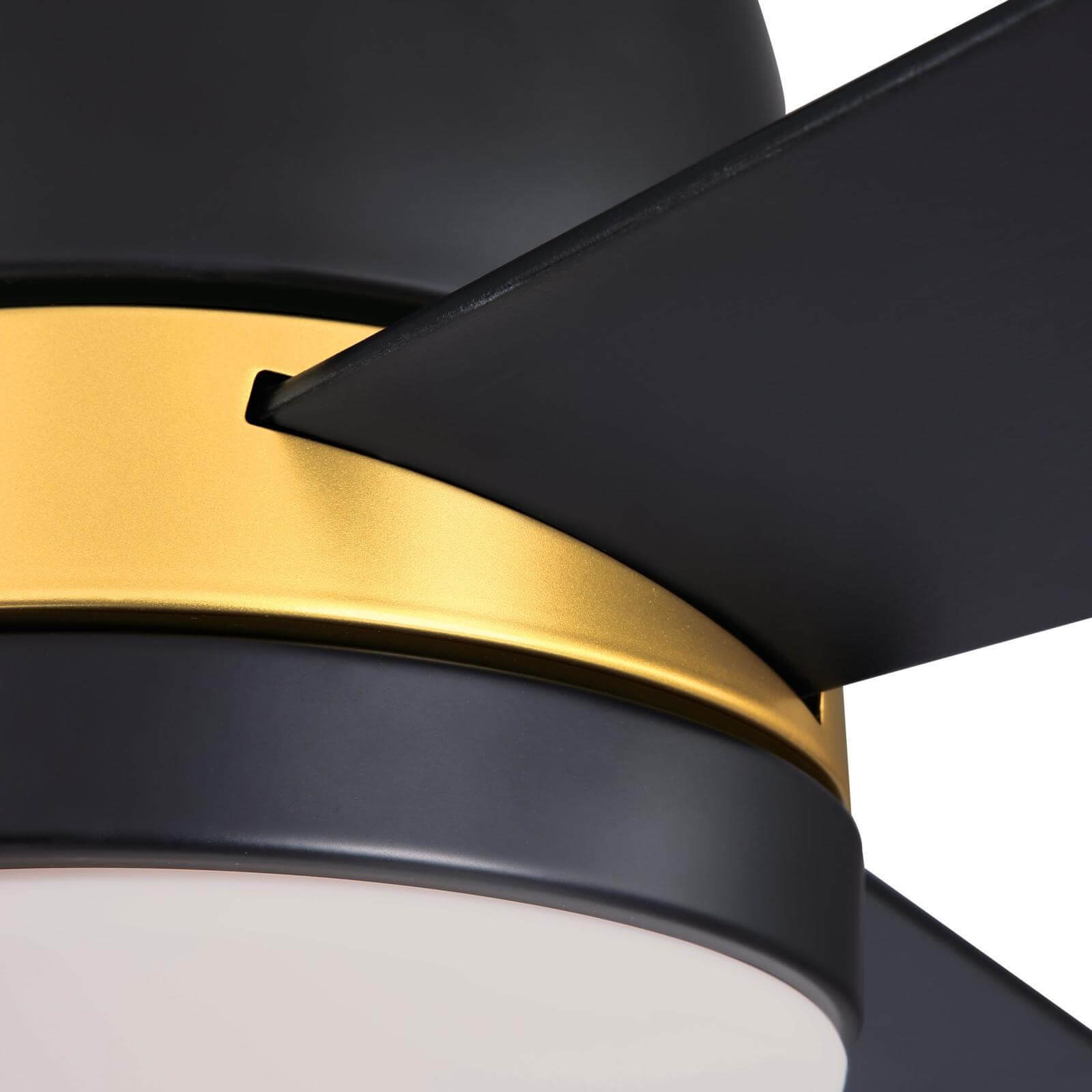 Ventilatore da soffitto nero con finiture dorate e pale nere. C'è una luce bianca.