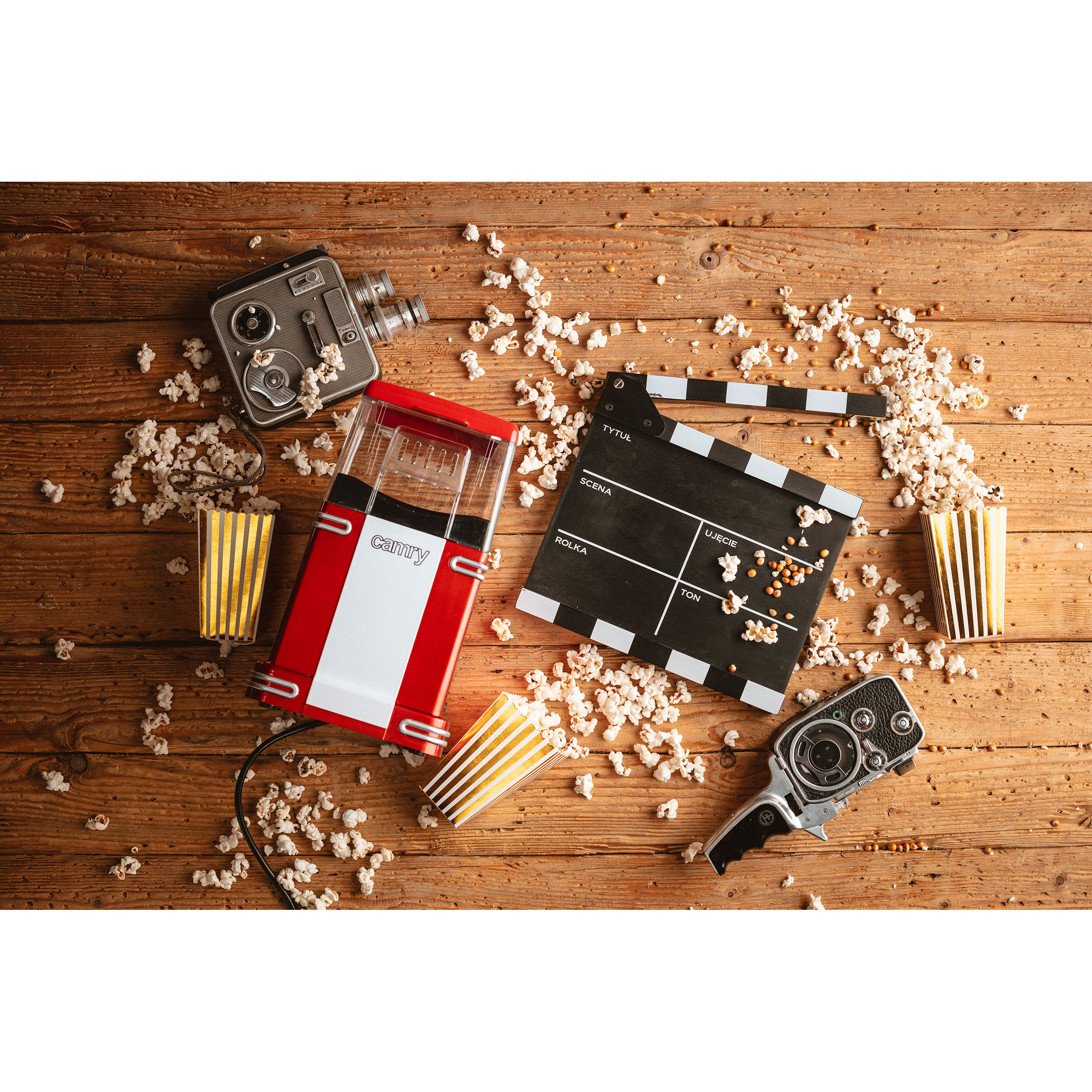 Máquina de palomitas y claqueta con palomitas y cámaras de cine en superficie de madera.