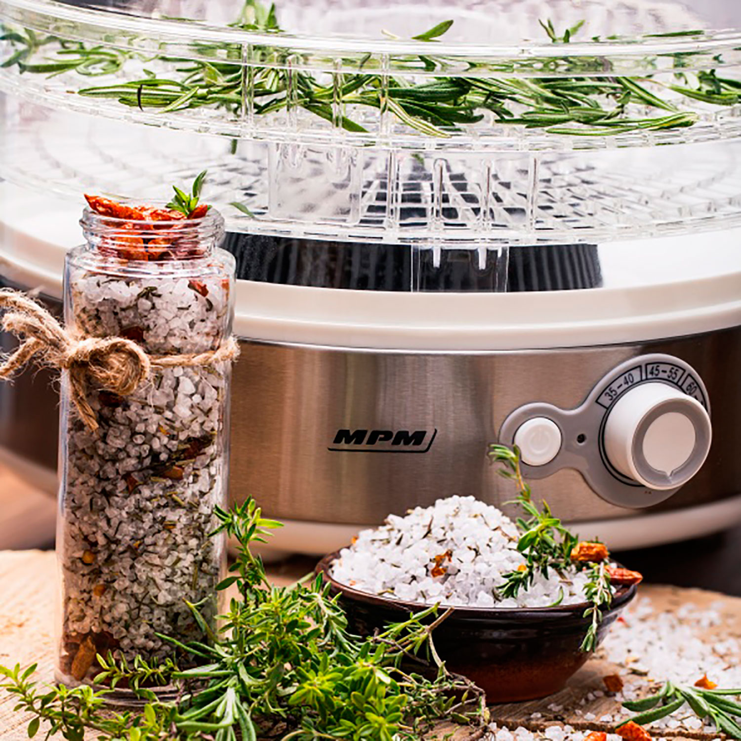 Deshidratador de alimentos con hierbas y especias, sal en un tarro de cristal. Secando hierbas. Superficie de madera.