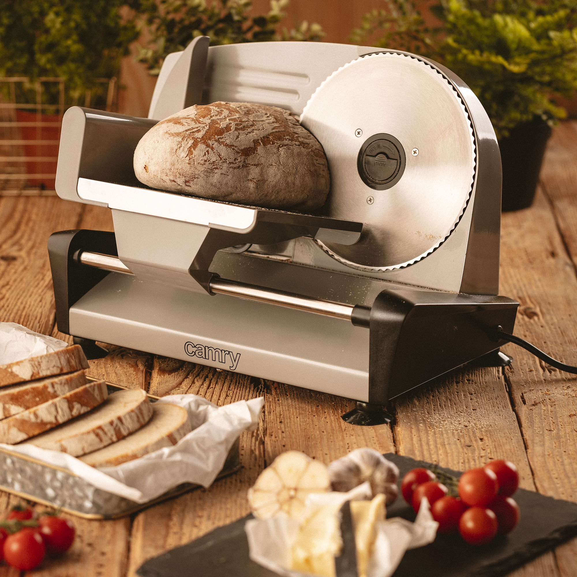 Krajacz do chleba z chlebem, masłem i pomidorami. Bochenek chleba jest krojony.