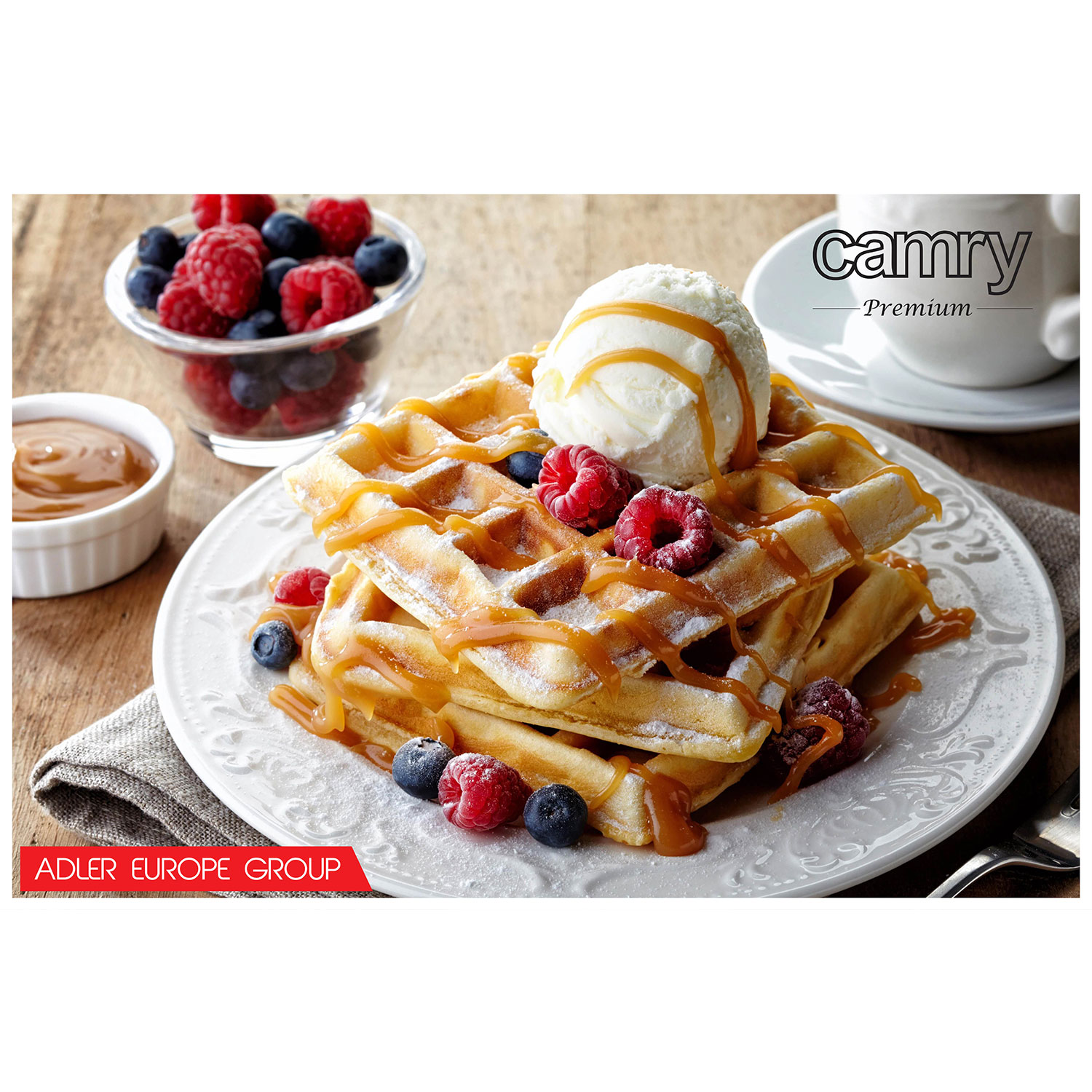 Waffeln mit Karamellsauce, Eis und Beeren auf einem weißen Teller.