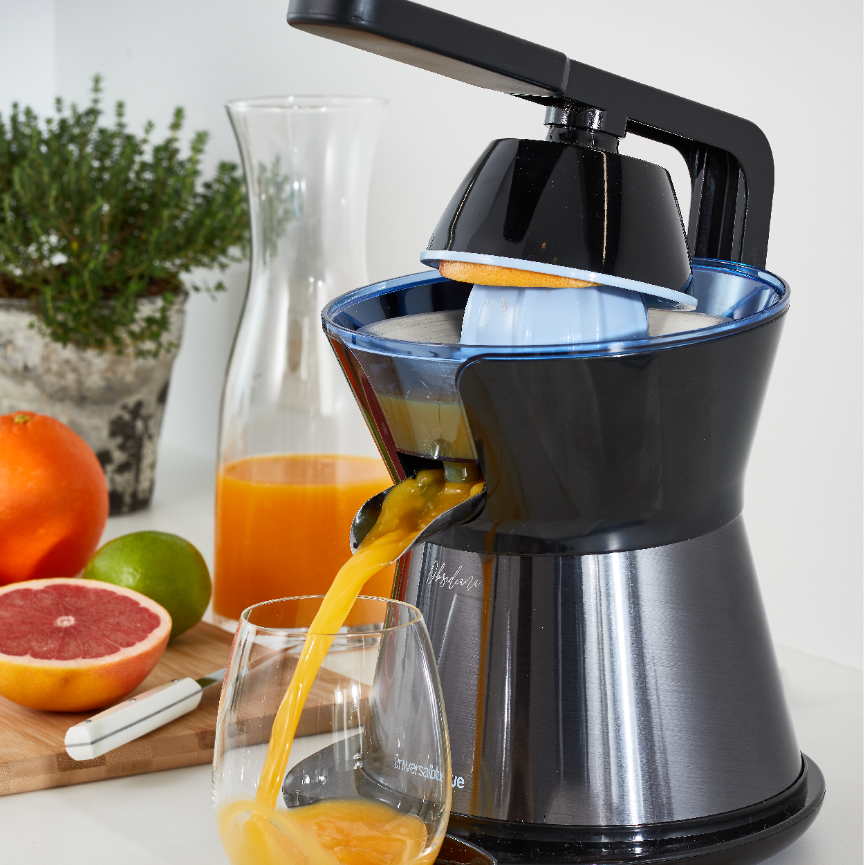 Una exprimidora vertiendo jugo de naranja en un vaso en una encimera.