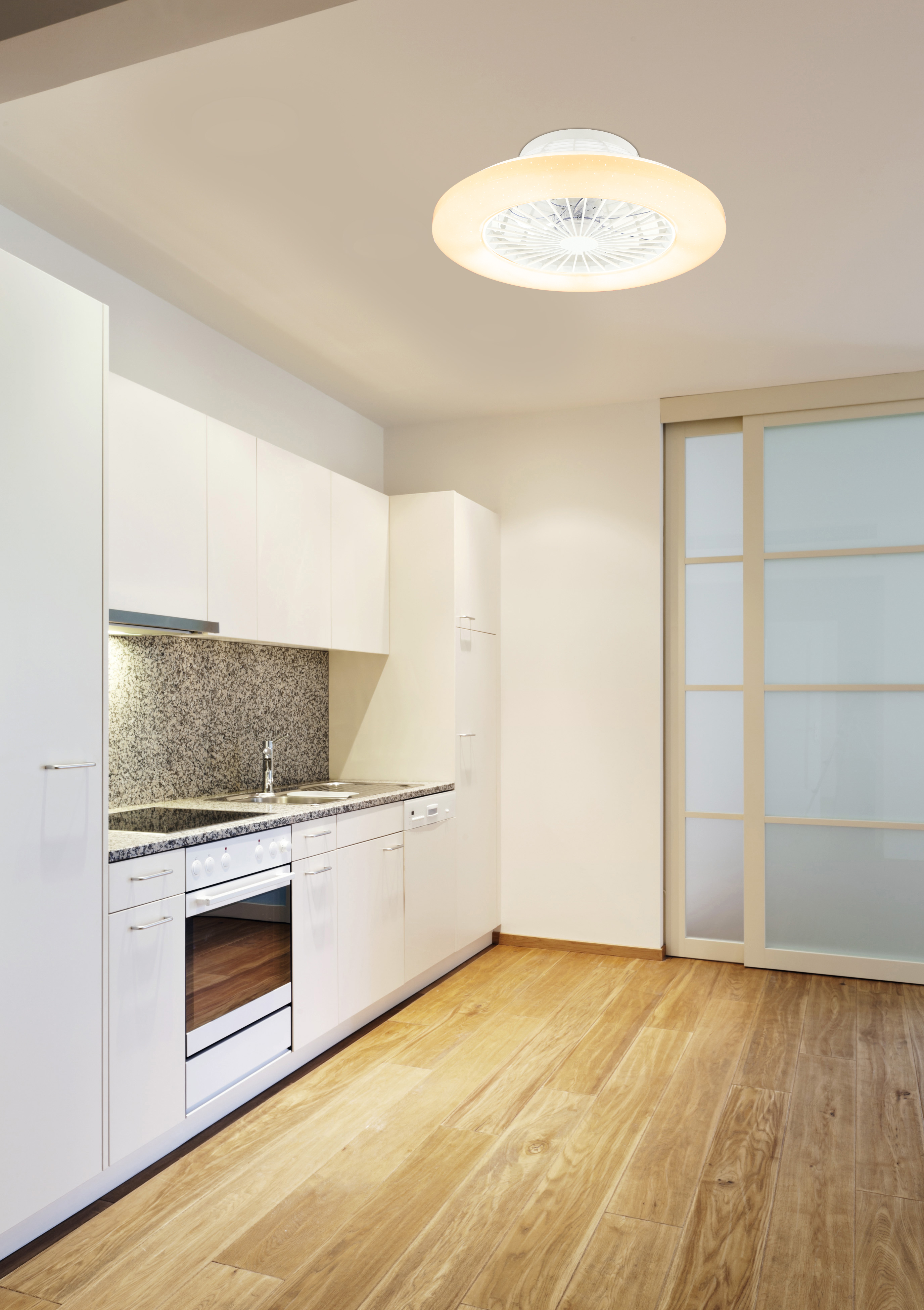 Kücheninnenraum mit weißen Schränken, Holzboden, Deckenventilator und Schiebetür.