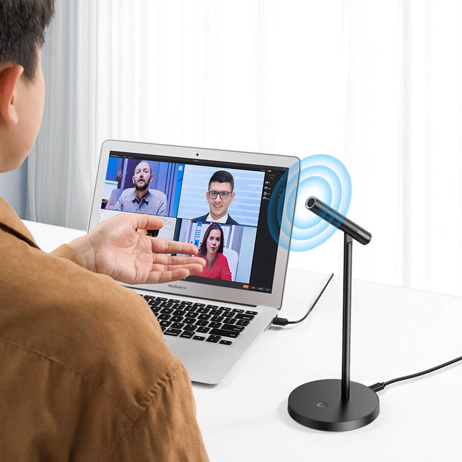 Mann benutzt Mikrofon für Videoanruf auf Laptop. Mikrofon steht auf einem Ständer.