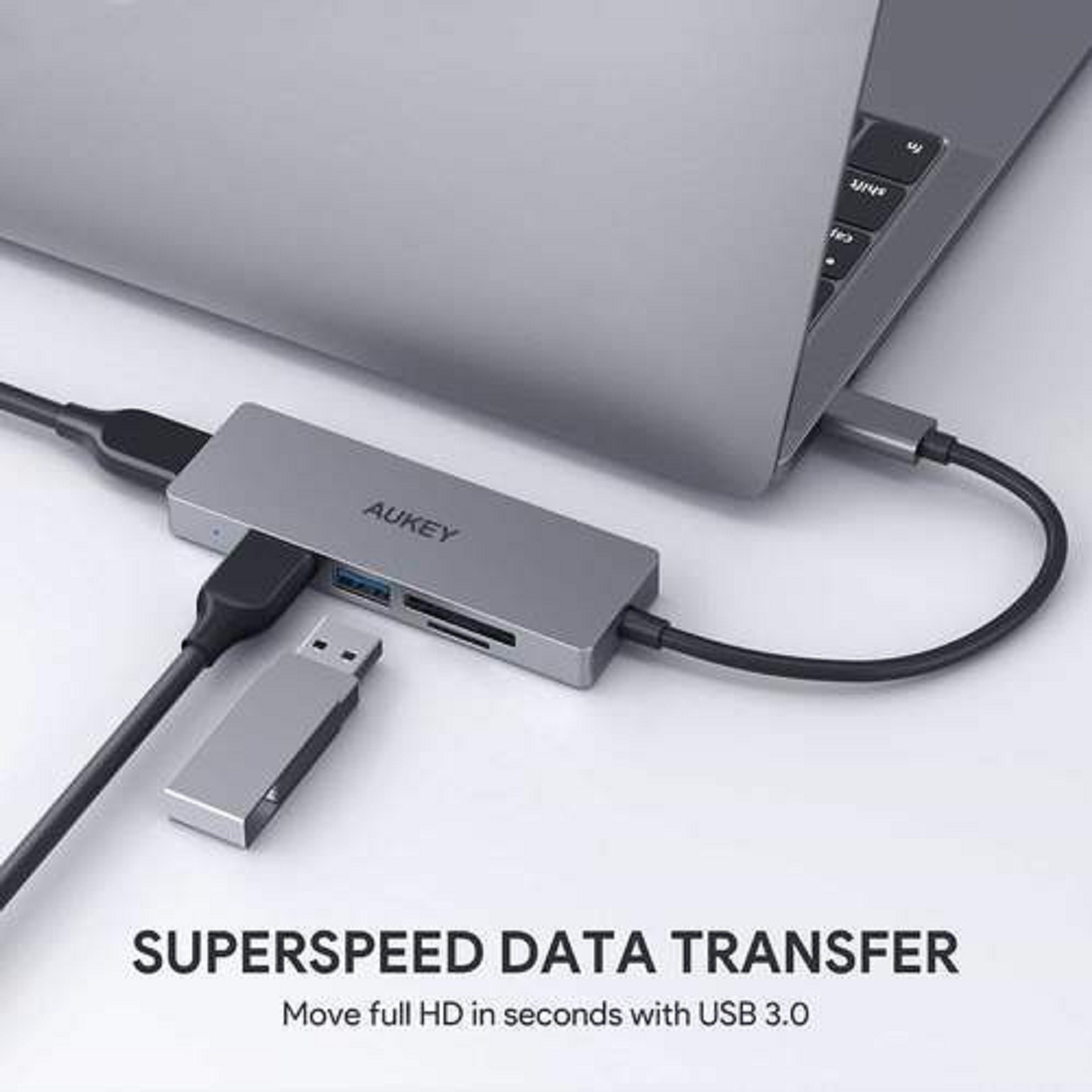 Silberner USB-Hub, an einen Laptop angeschlossen, mit USB-Stick und Text: Superspeed Data Transfer.