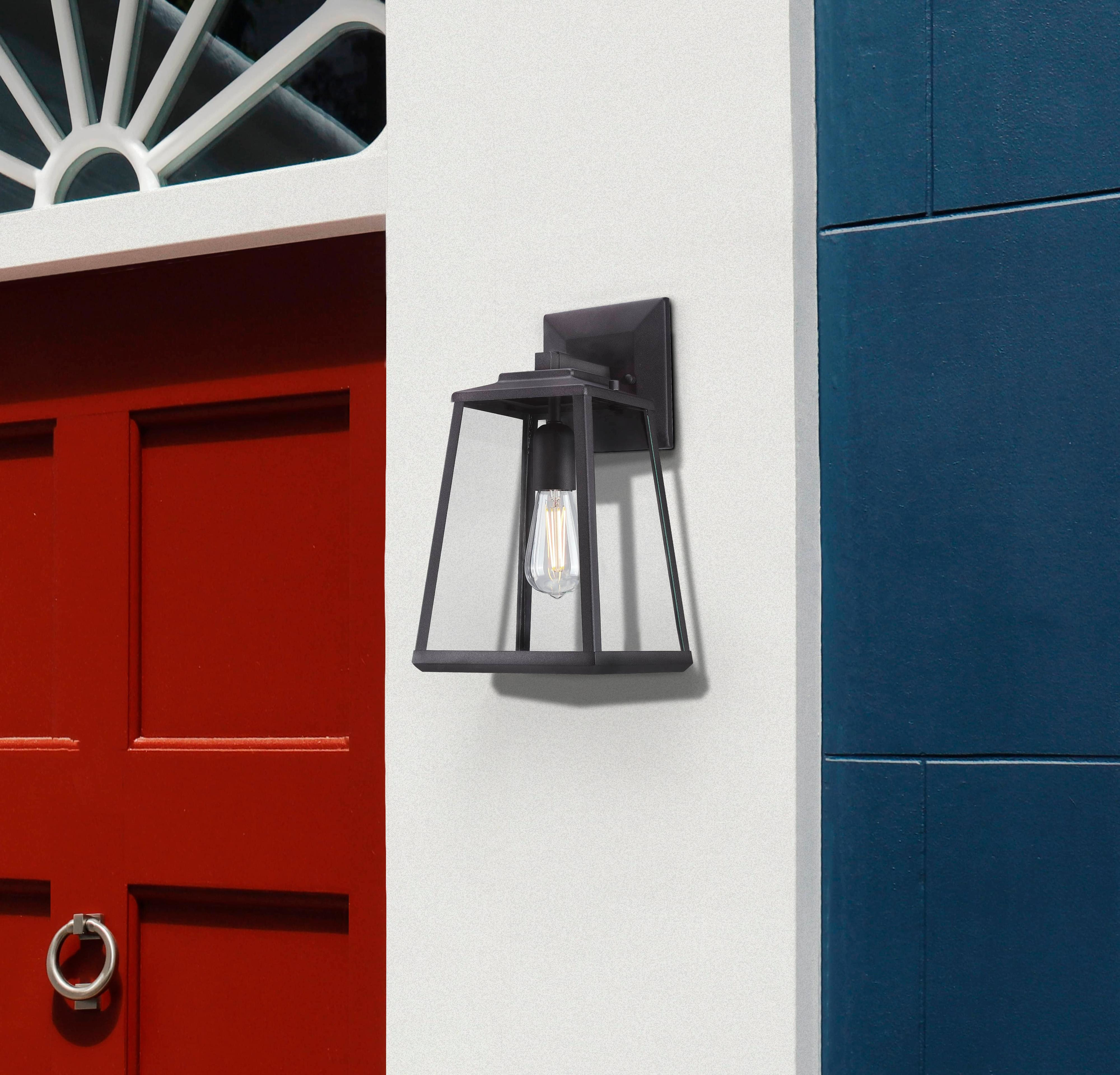 Eine schwarze Außenlampe an einer weißen Wand zwischen roten und blauen Wänden.