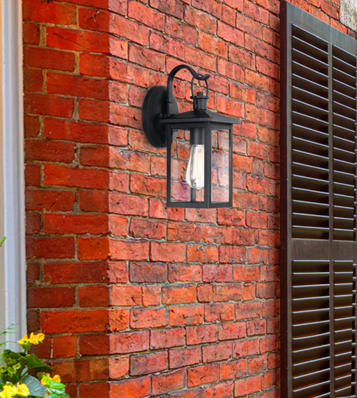 Schwarze Außenwandleuchte an einer roten Backsteinmauer mit dunkler Jalousie.