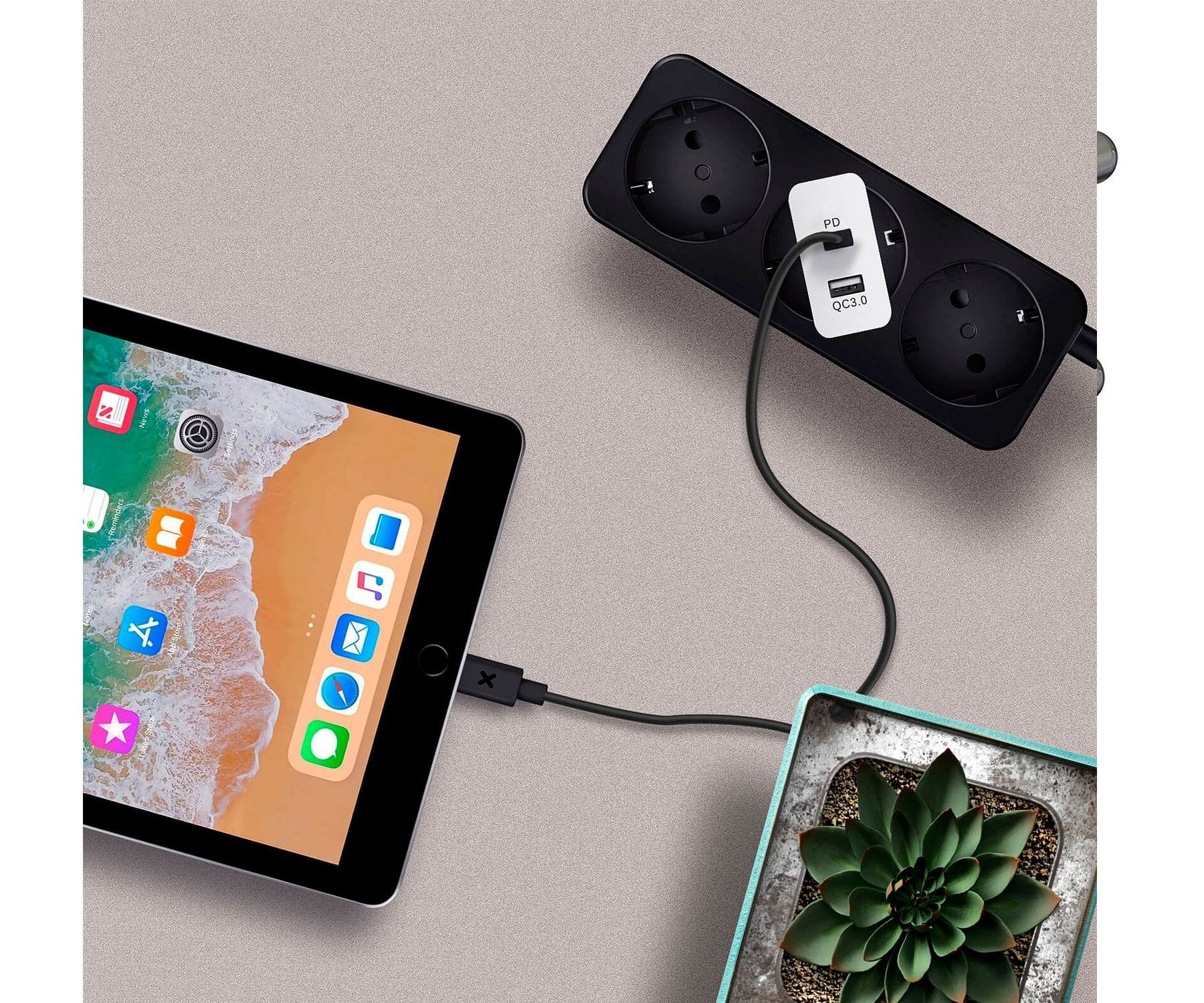 Tablet collegato a ciabatta e pianta. Cavo nero, sfondo bianco. Configurazione moderna.