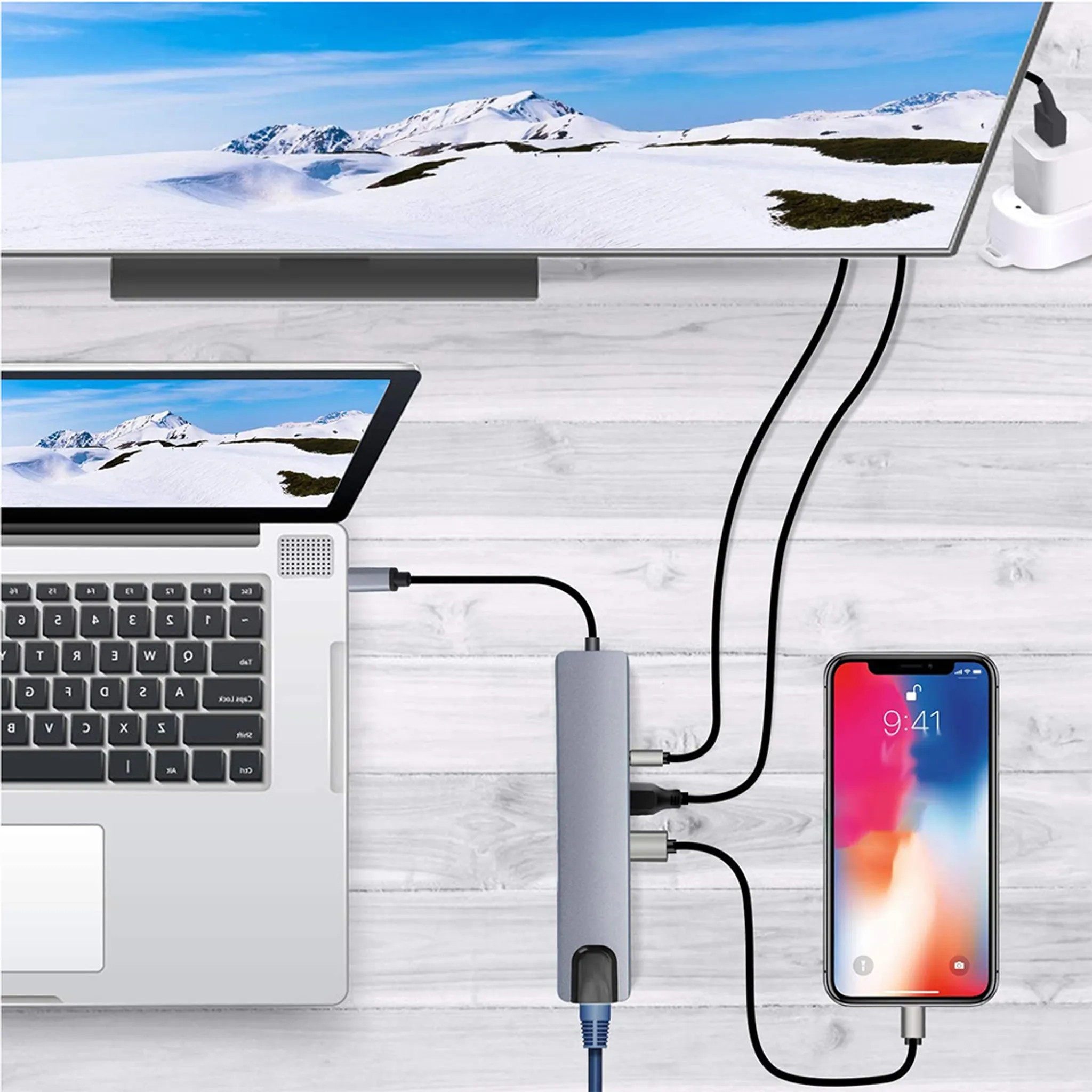 Laptop, Telefon und andere Geräte sind über Kabel mit einem grauen USB-Hub verbunden.