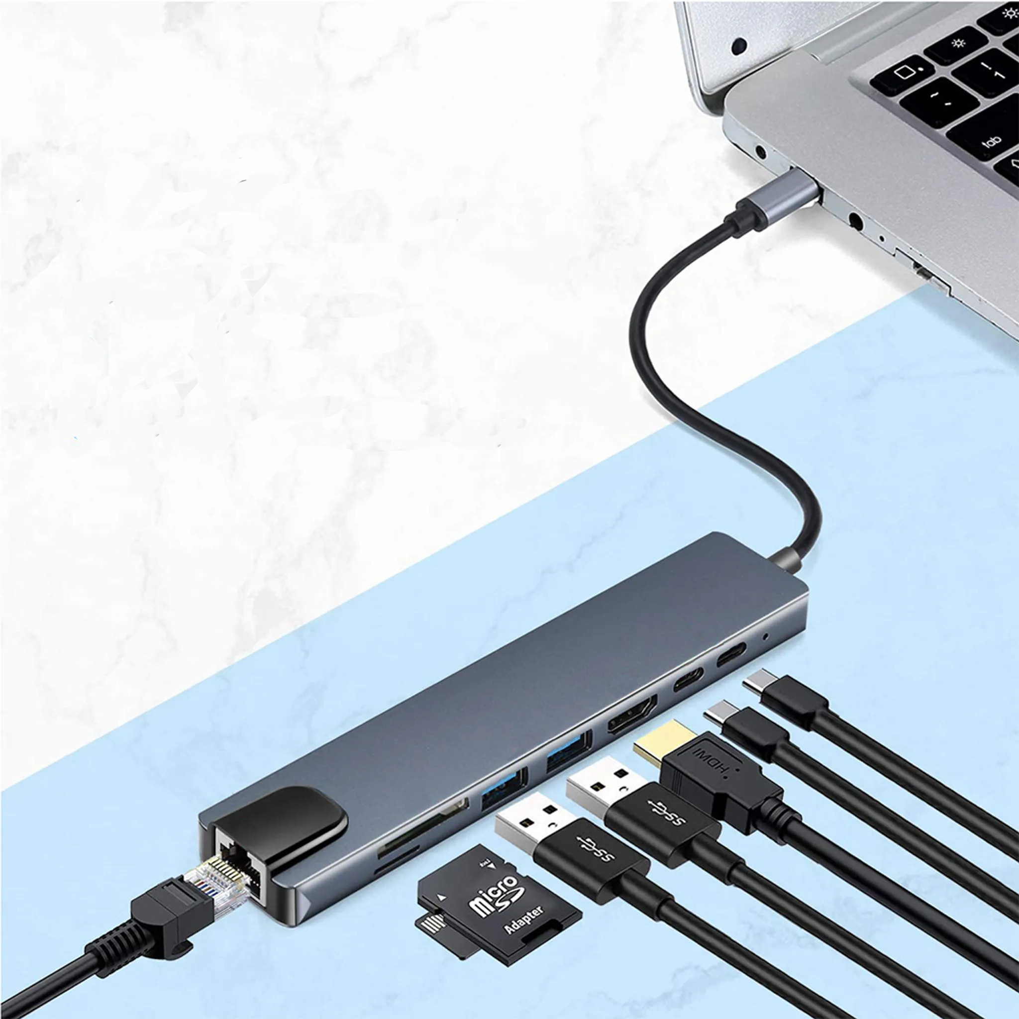 Ein Hub mit Anschlüssen, die mit einem Laptop verbunden sind. Kabel, ein Micro-SD-Adapter und USB-Laufwerke sind ebenfalls abgebildet.