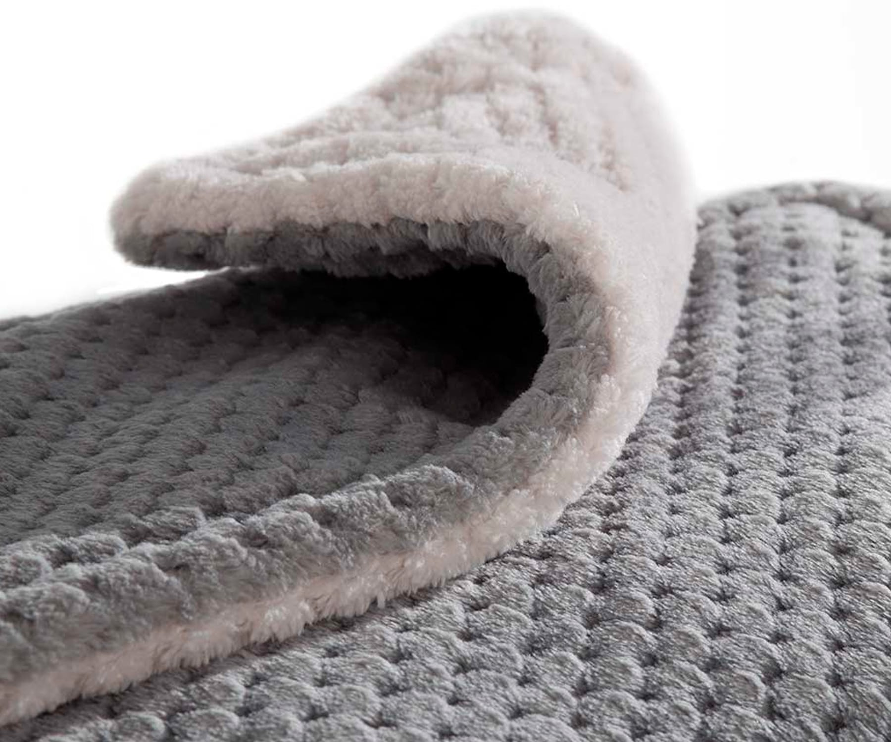 Primer plano de una alfombra texturizada gris y blanca con un diseño en capas y bordes suaves.
