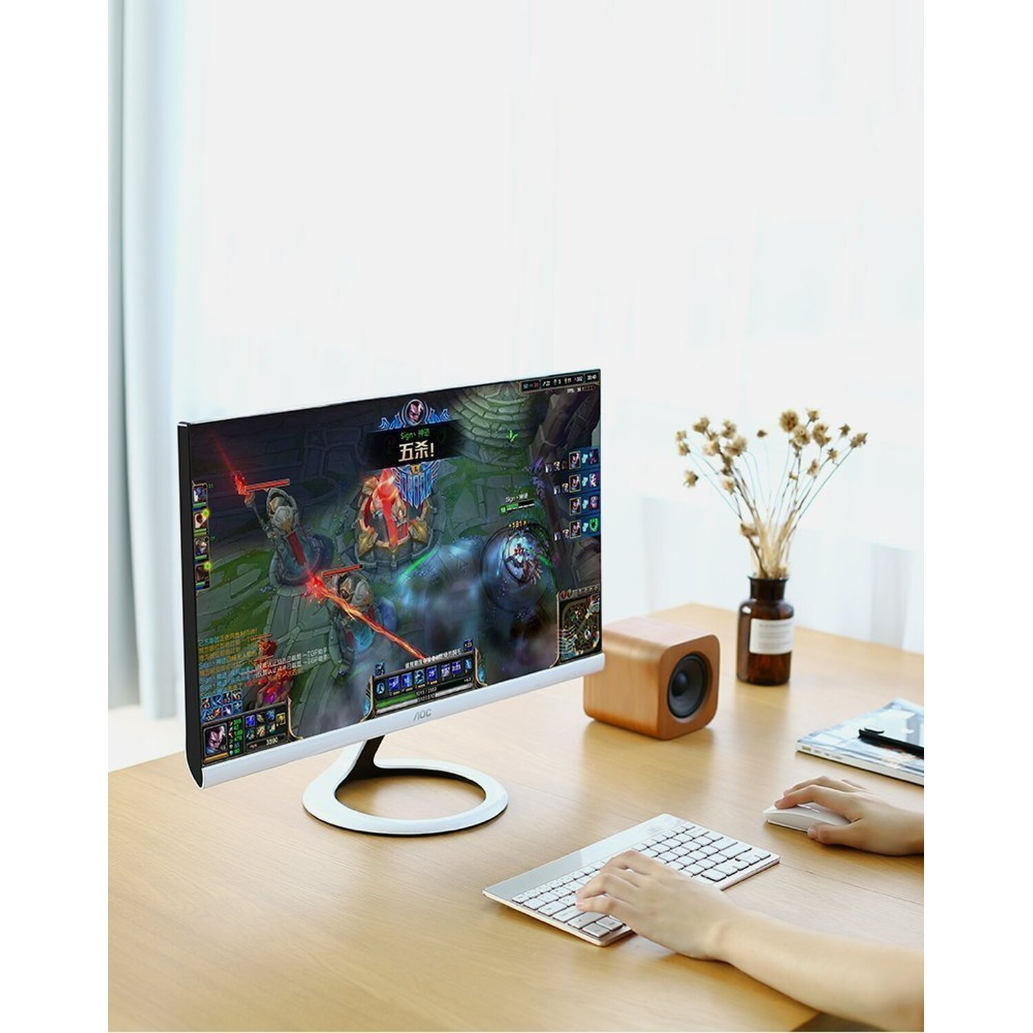 Konfiguracja komputera stacjonarnego z monitorem pokazującym grę, głośnikiem i klawiaturą. Ręce używają klawiatury.