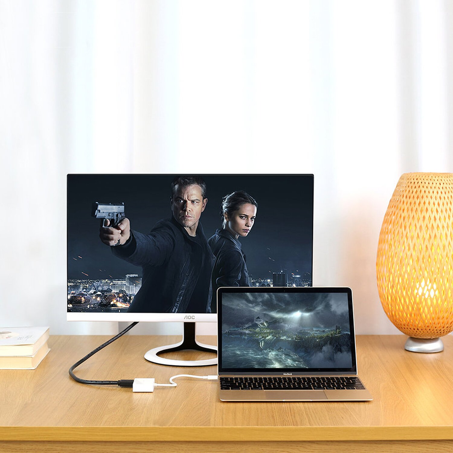 Monitor mit Filmszene. Laptop angeschlossen. Holzschreibtisch und weiße Vorhänge im Hintergrund.
