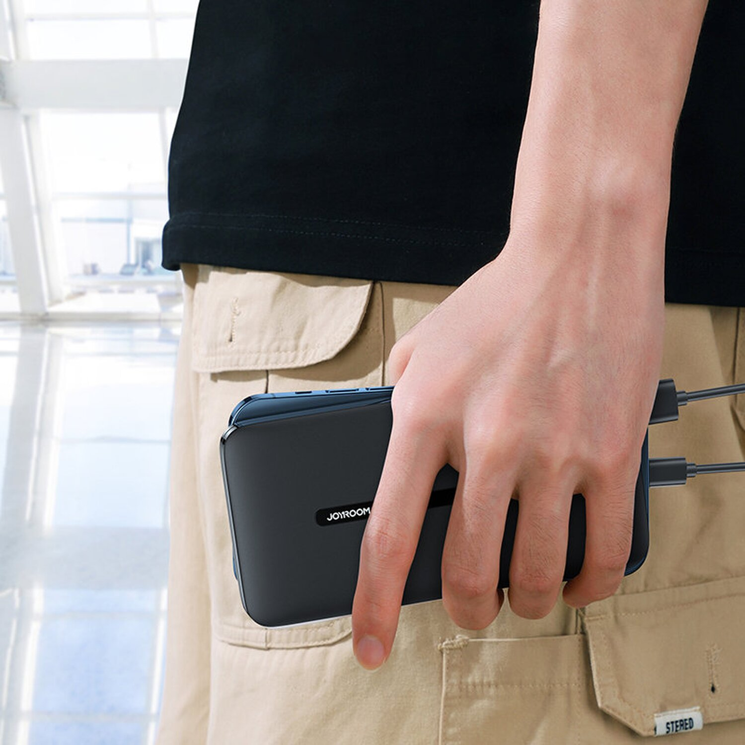 Eine Person hält eine schwarze und blaue Powerbank.
