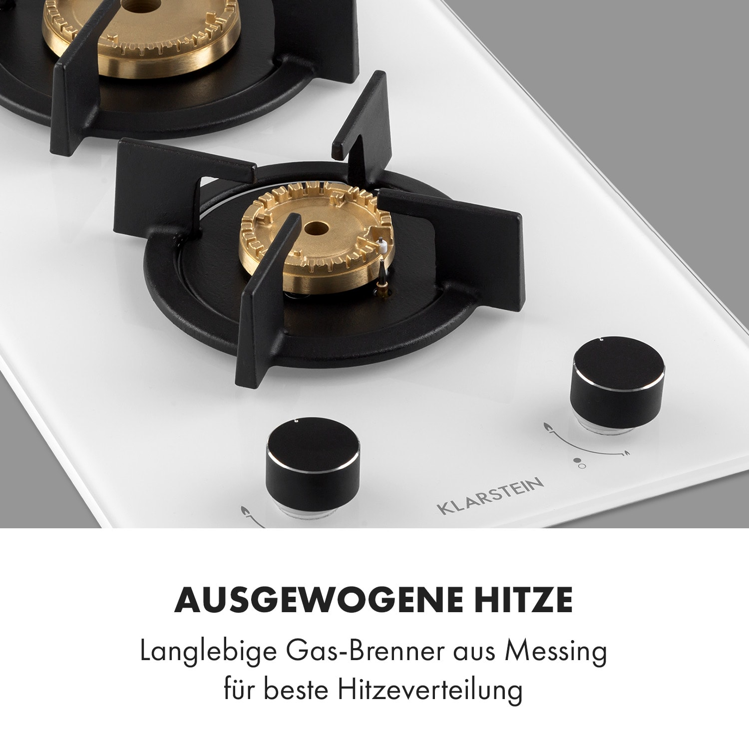 Nahaufnahme eines weißen Gasherds mit Messingbrennern und schwarzen Knöpfen.