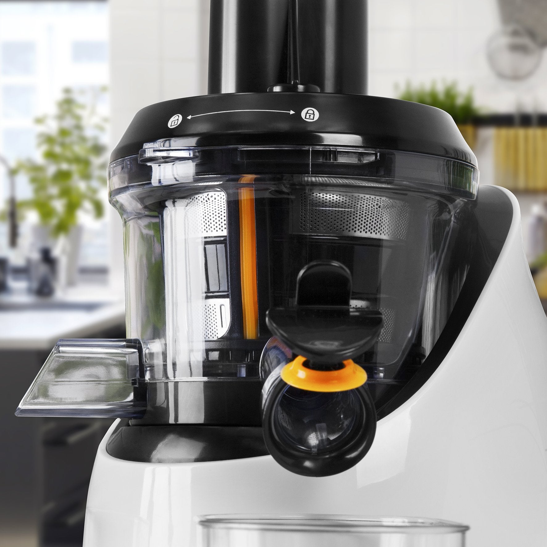 Primer plano de una máquina de zumos. Blanco y negro con acento naranja. Fondo borroso.