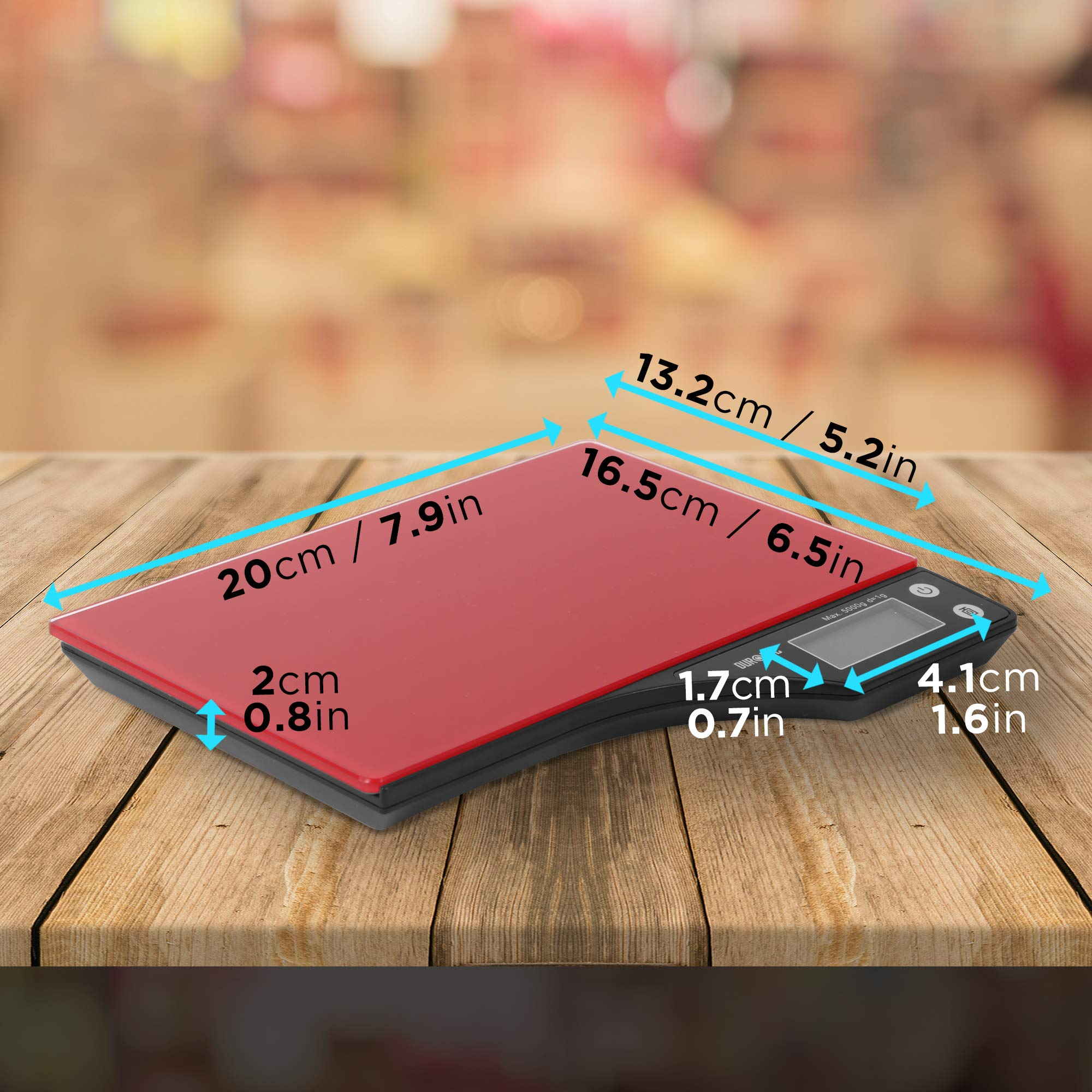 Una báscula de cocina digital roja y negra con dimensiones etiquetadas. La báscula está sobre una mesa de madera.