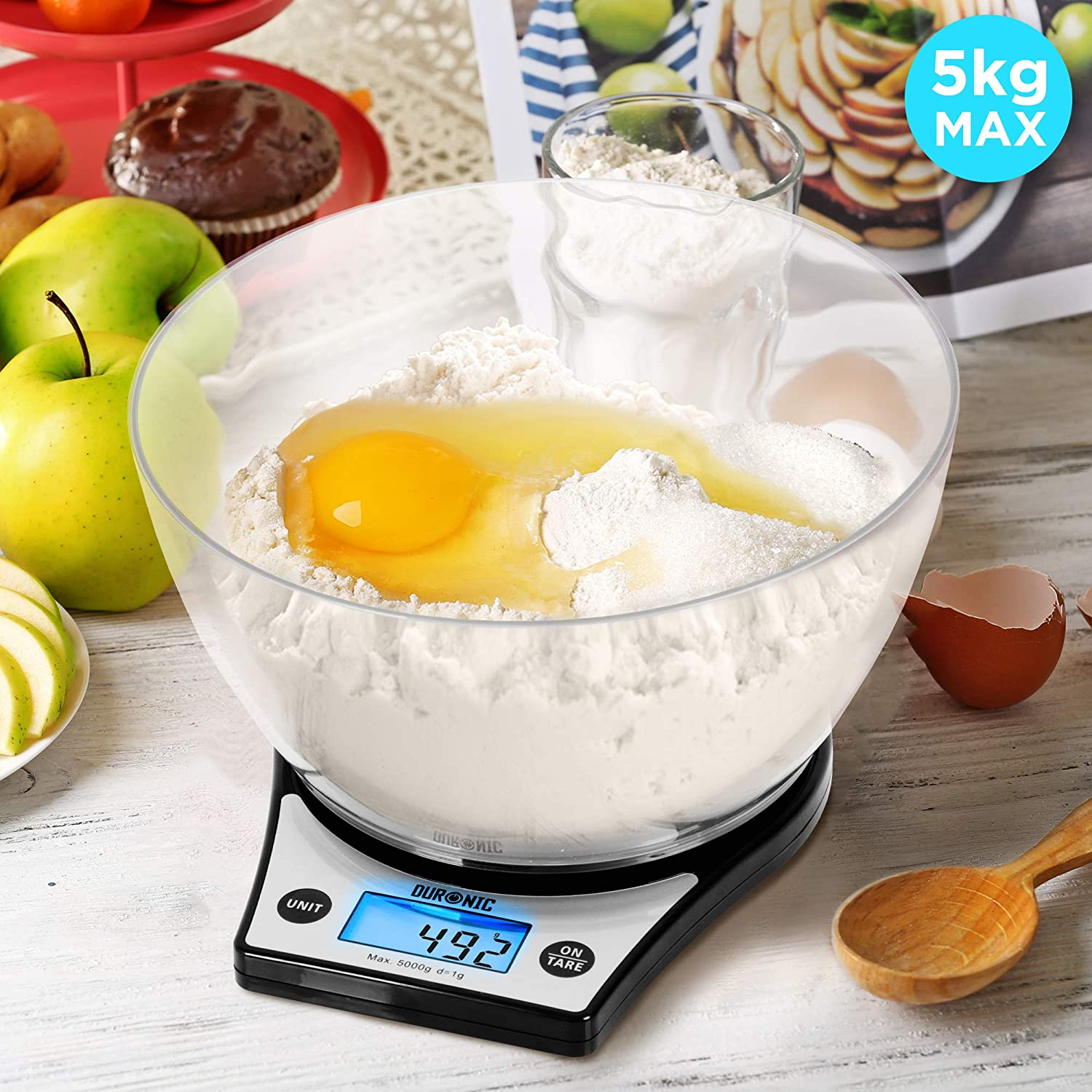 Digitale Küchenwaage mit Zutaten in einer Schüssel und Obst drumherum.
