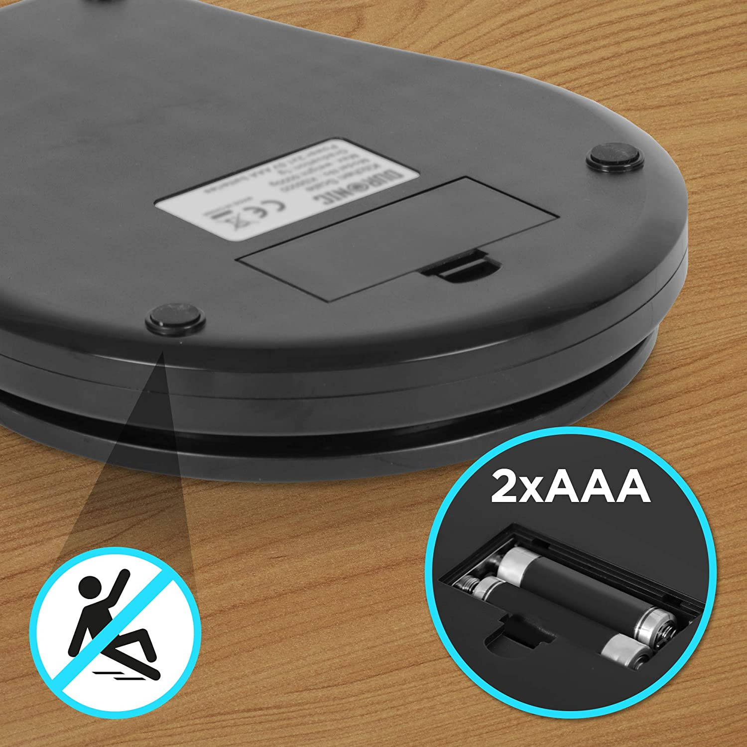 Unterseite einer schwarzen Waage mit Batteriefach, Batterien und einem Warnsymbol.