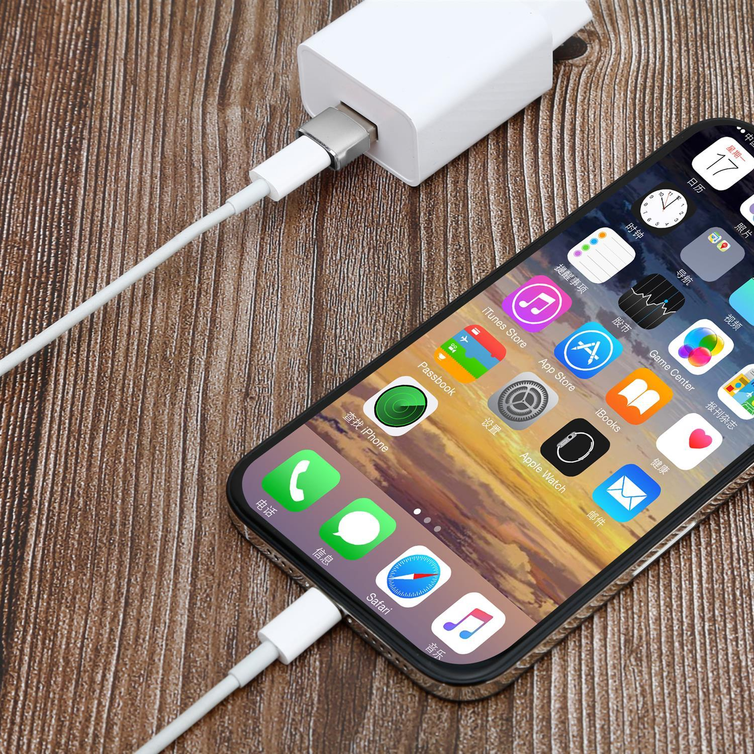 Un teléfono conectado a un cargador blanco. La pantalla del teléfono muestra aplicaciones y está en una mesa de madera.
