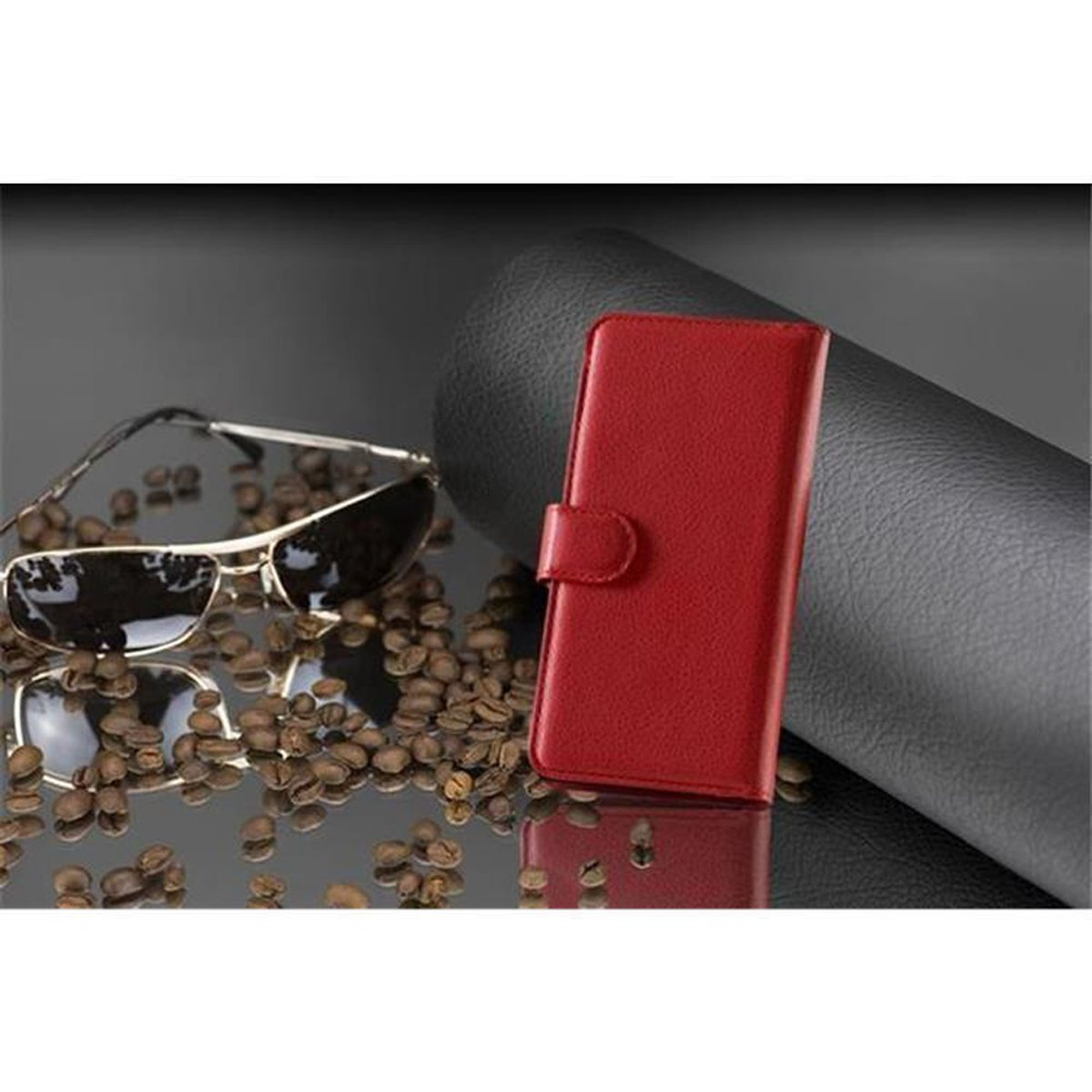 Una custodia rossa per telefono è chiusa, con occhiali da sole e chicchi di caffè su una superficie riflettente.