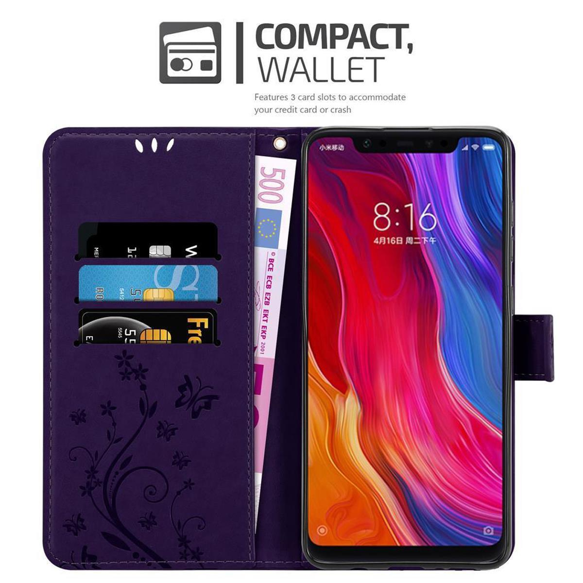 Custodia a portafoglio viola aperta con carte e denaro. Schermo del telefono acceso. Design floreale. Sfondo bianco.